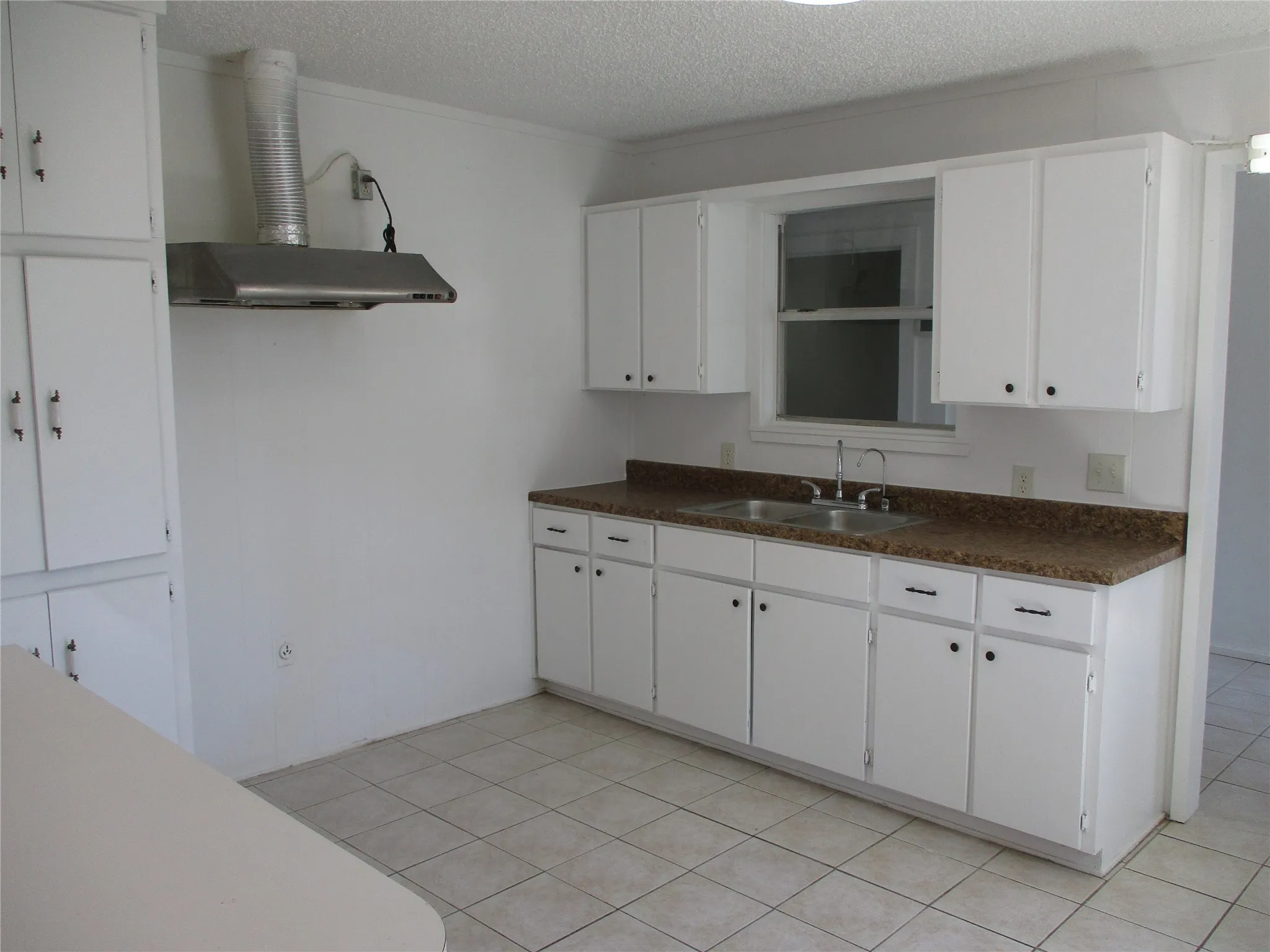 Kitchen featuring a sink, dark countertops, white cabinetry, and a textured ceiling