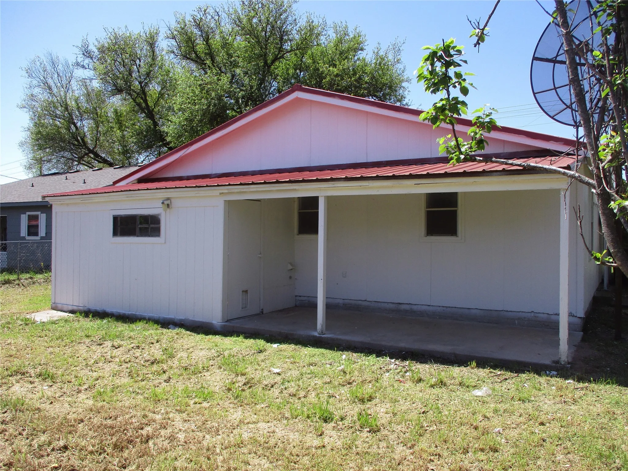 Rear view of property with a yard, metal roof, a patio area, and fence