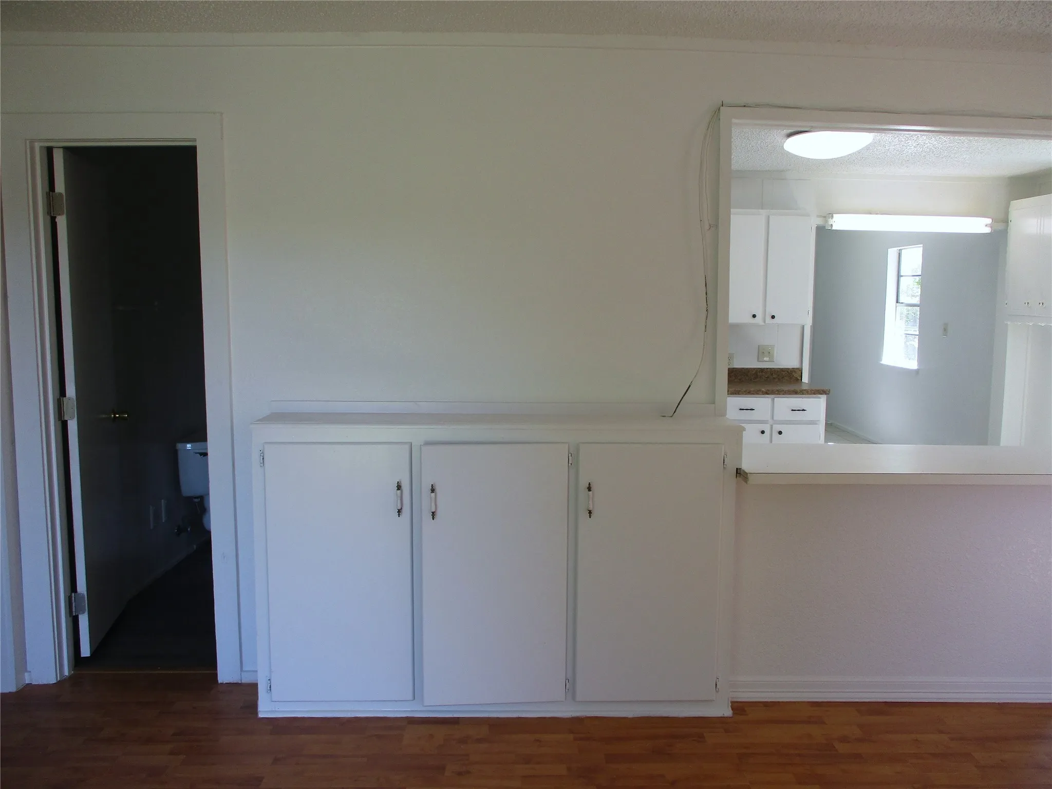 Kitchen featuring a textured ceiling, white cabinetry, and wood finished floors