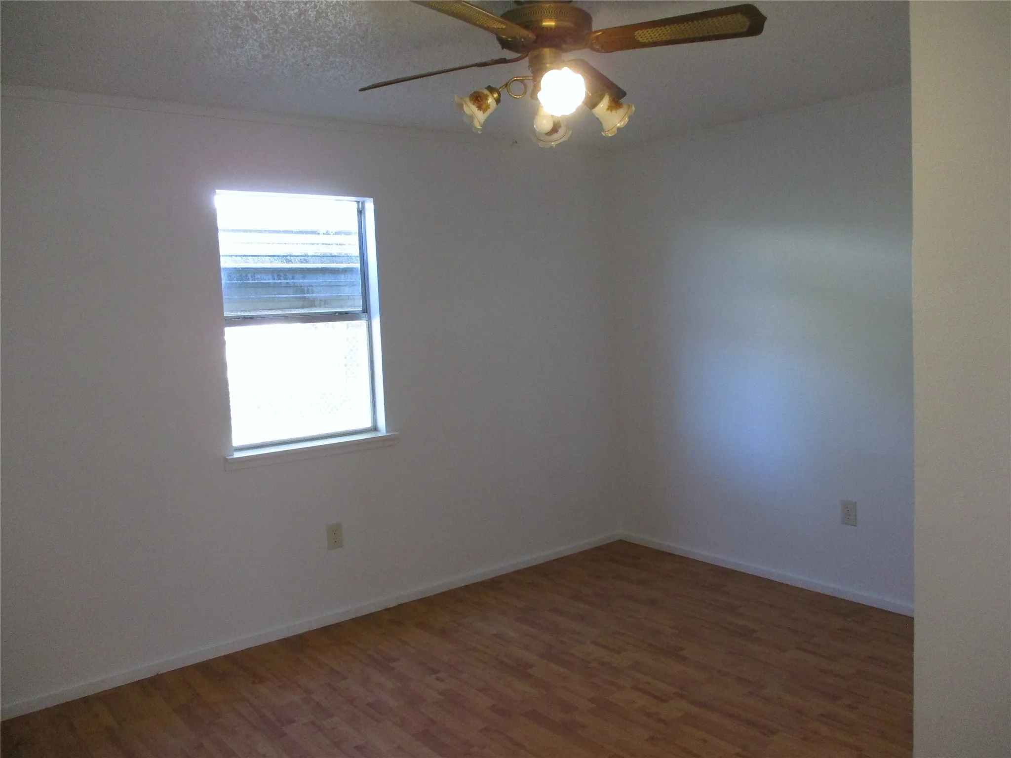 Empty room with baseboards, a ceiling fan, wood finished floors, and a textured ceiling
