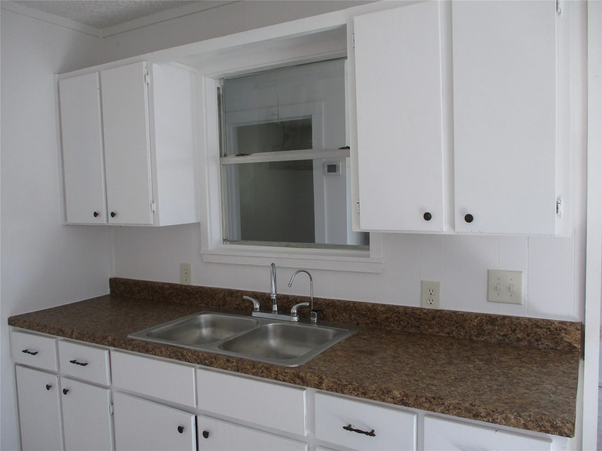Kitchen with a sink, white cabinets, and dark countertops