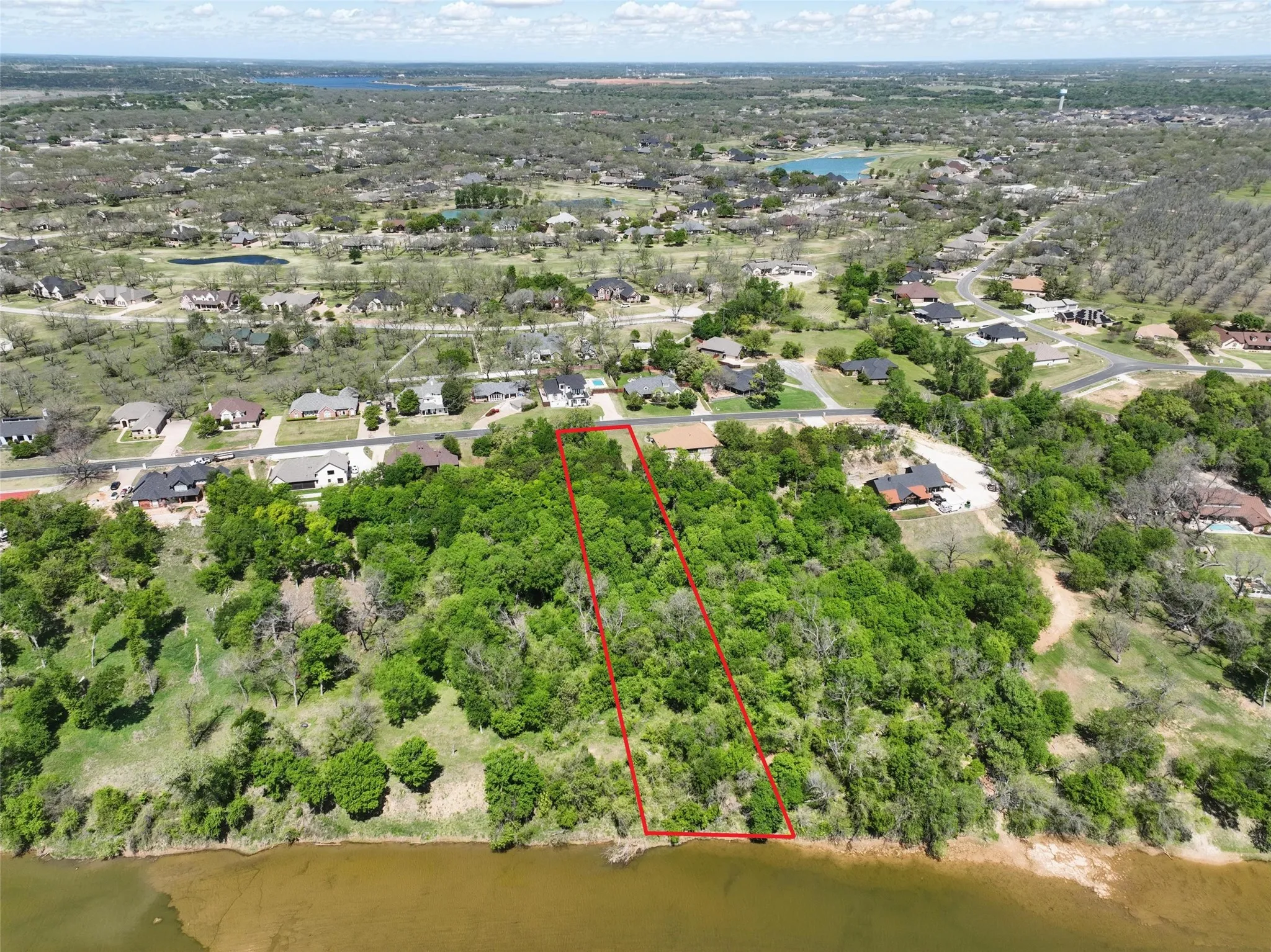 Elevated aerial view capturing river frontage and lush canopy of trees.