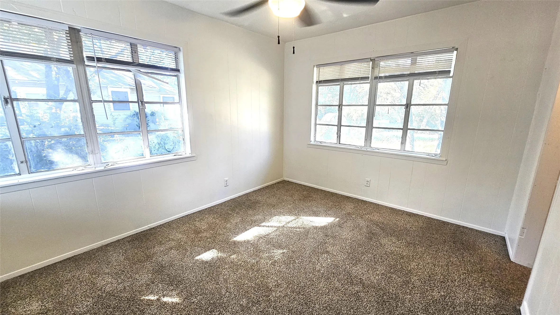 Carpeted spare room with plenty of natural light and ceiling fan