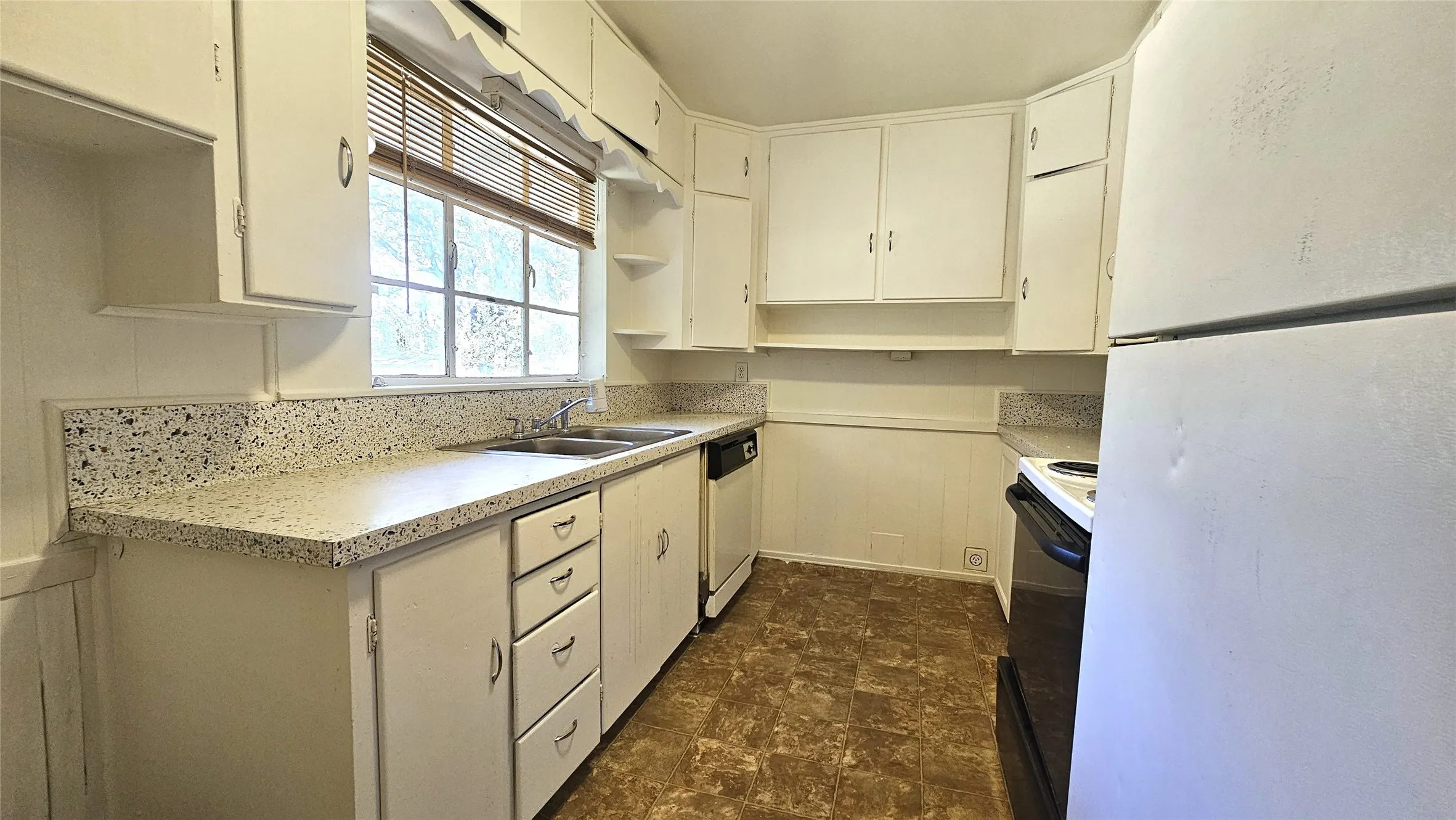 Kitchen with white appliances, light countertops, stone finish floors, open shelves, and white cabinets