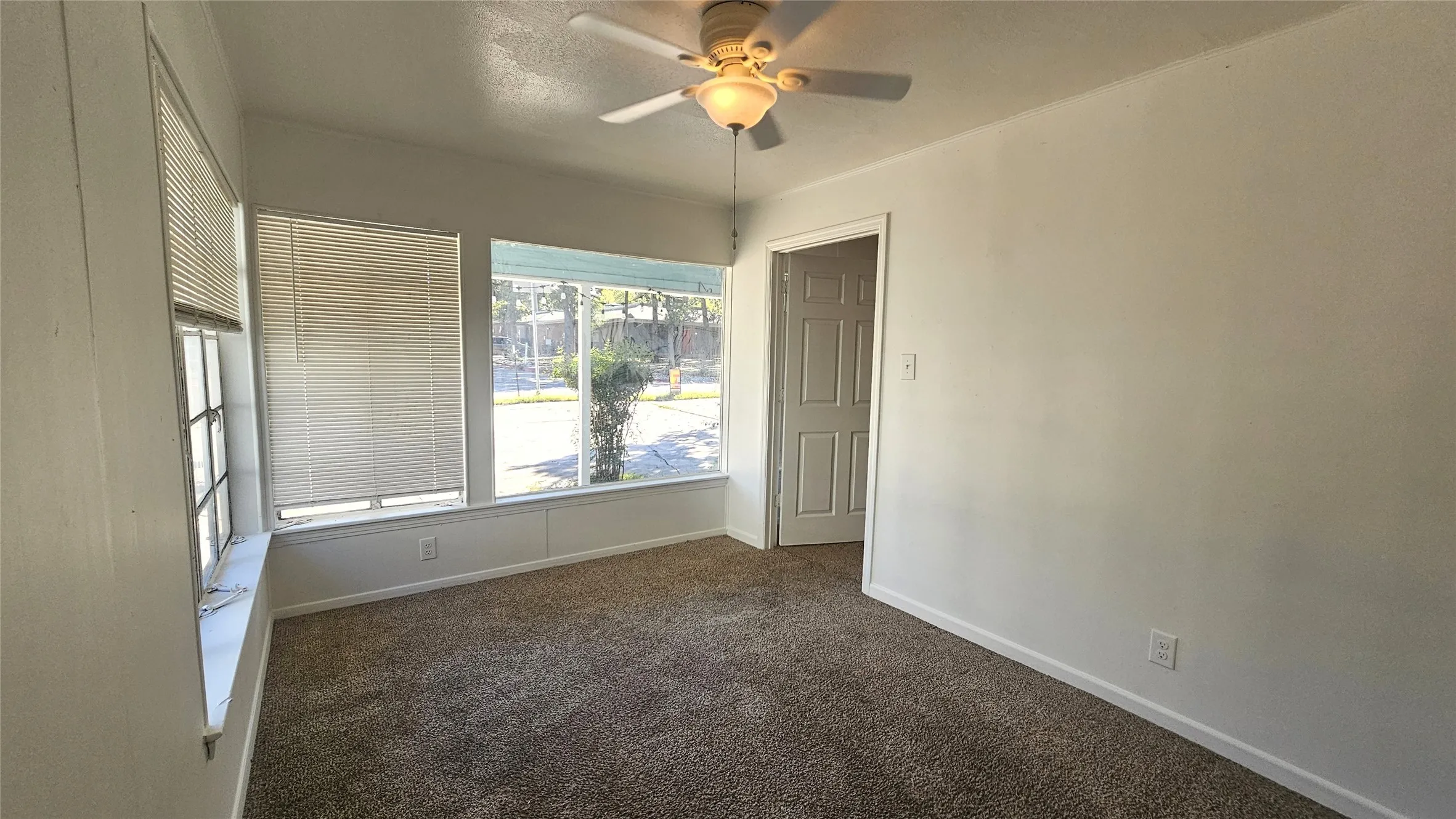 Spare room featuring dark colored carpet and ceiling fan