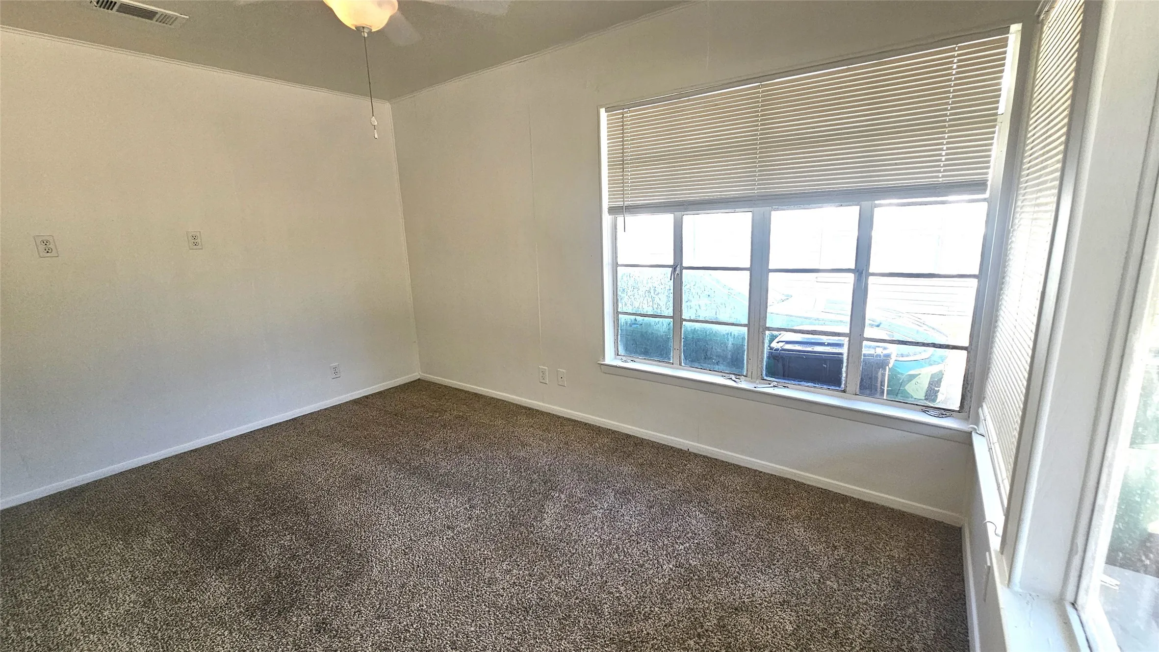 Empty room with dark carpet and a ceiling fan
