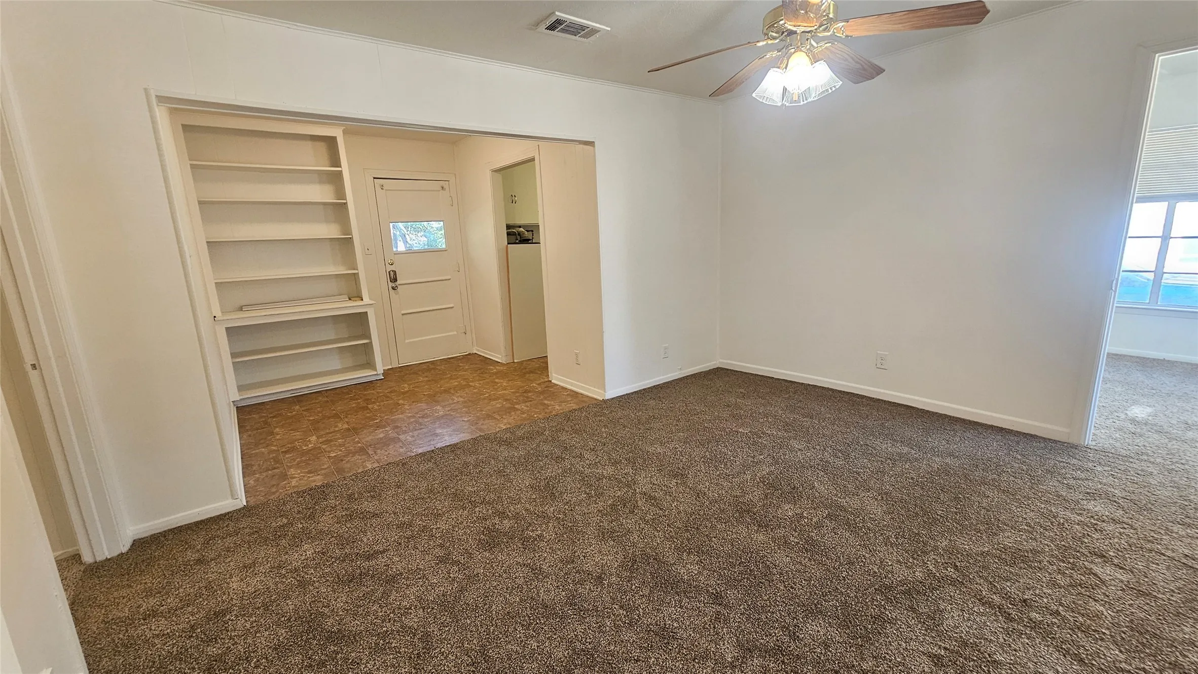 Spare room with built in features, dark carpet, and ceiling fan