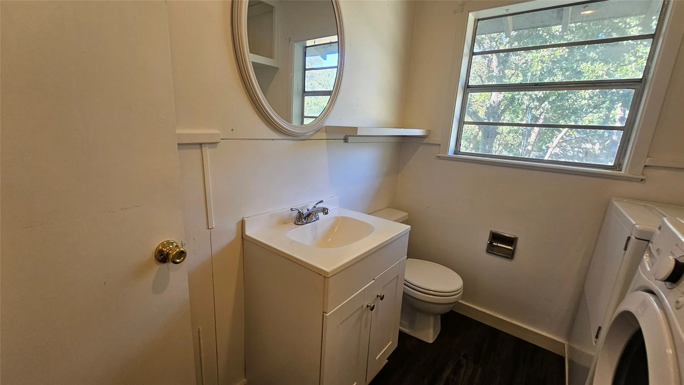 Half bath featuring vanity, separate washer and dryer, and dark wood-type flooring