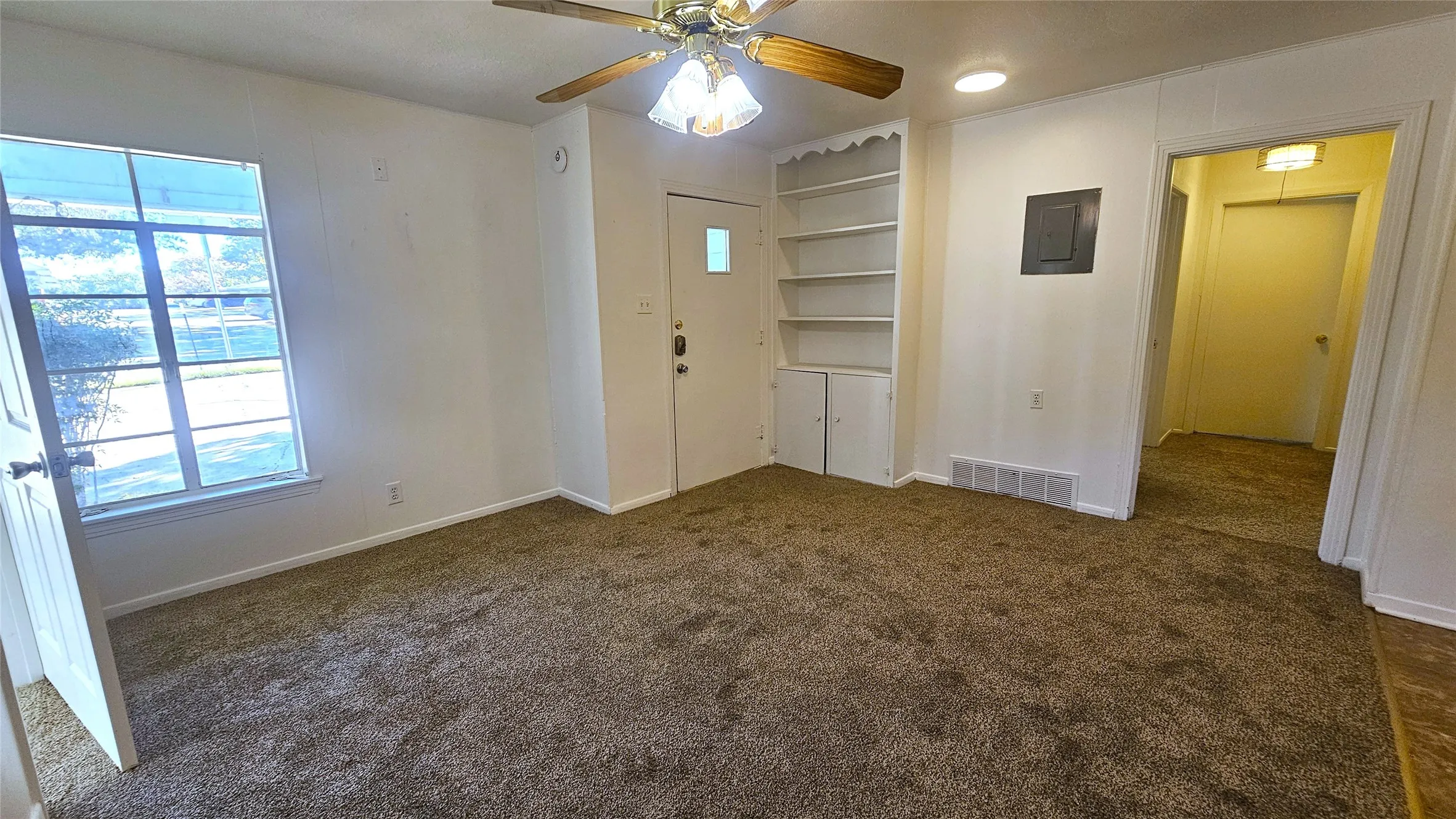 Entrance foyer with a ceiling fan, dark carpet, and electric panel