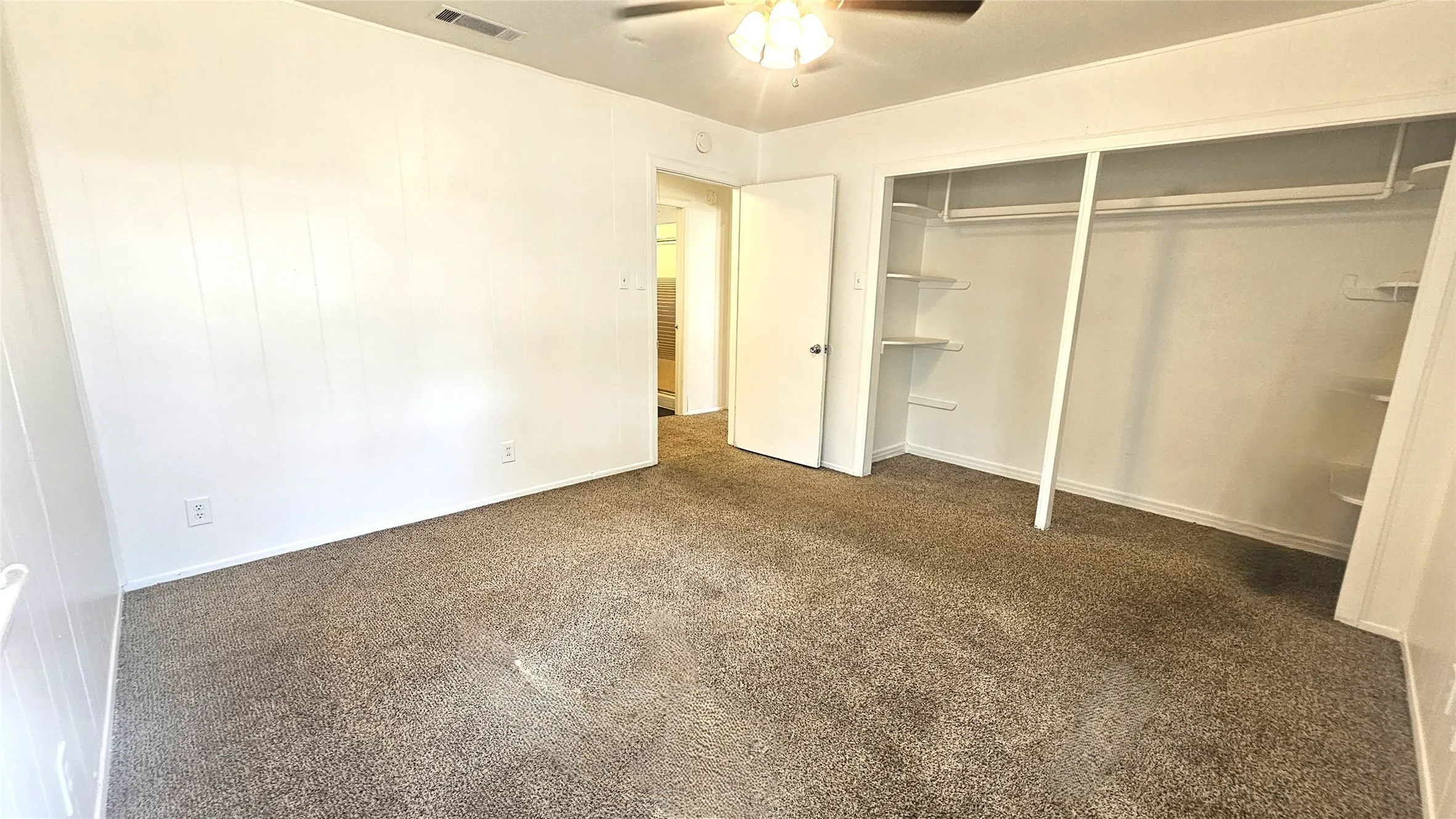 Unfurnished bedroom with dark colored carpet, a ceiling fan, and a closet