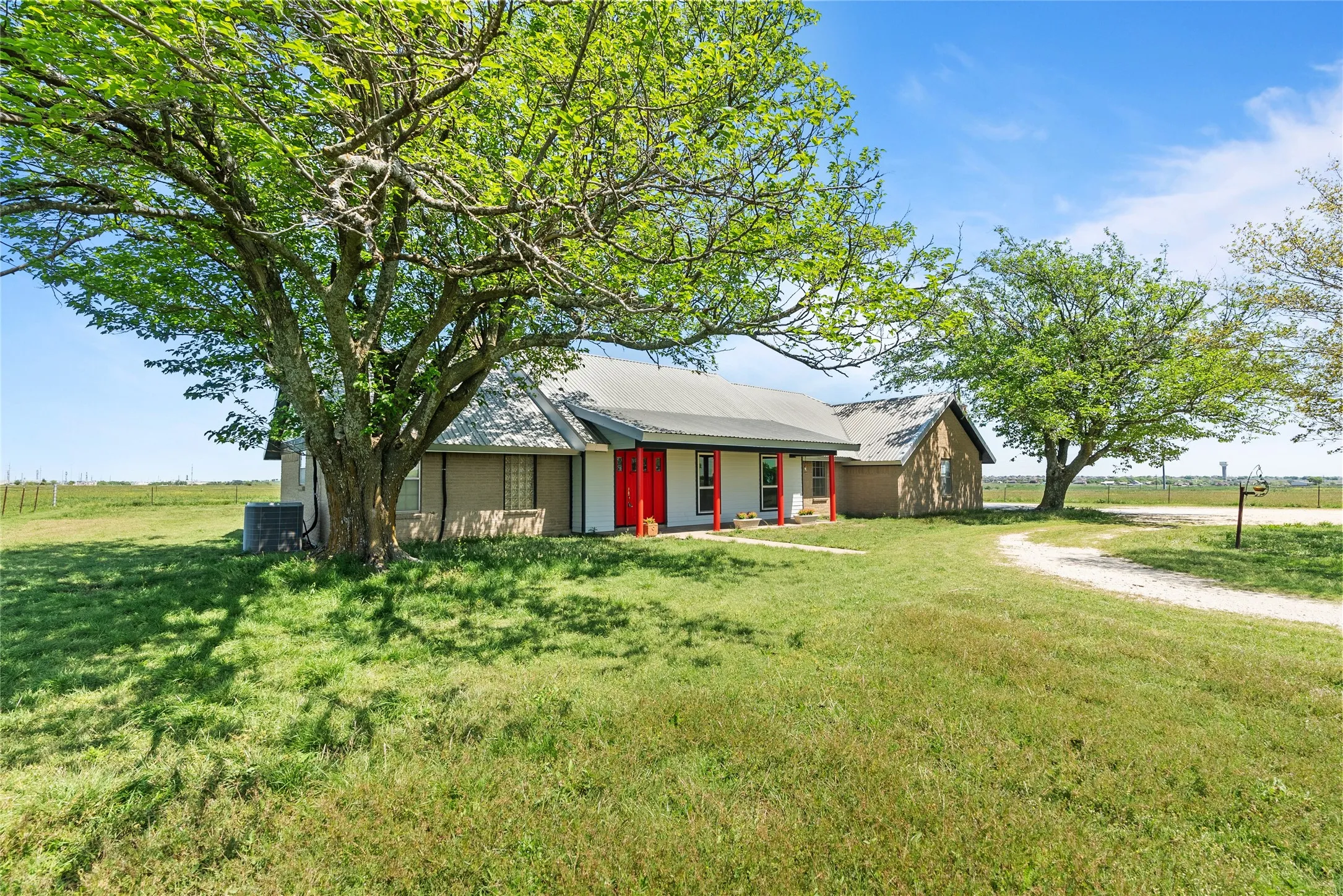 View of front of property featuring metal roof, central air condition unit, and a front lawn