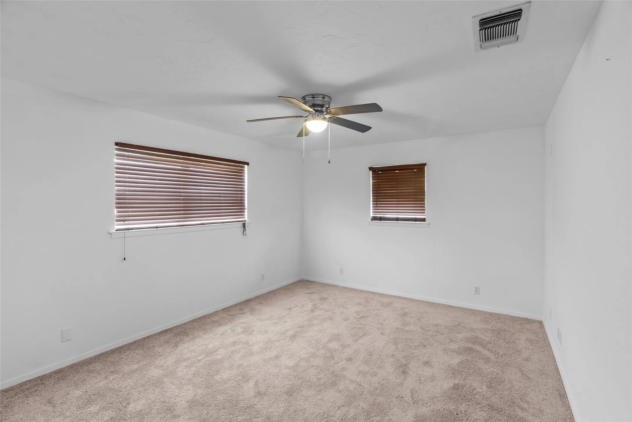 Empty room featuring visible vents, ceiling fan, baseboards, and carpet floors