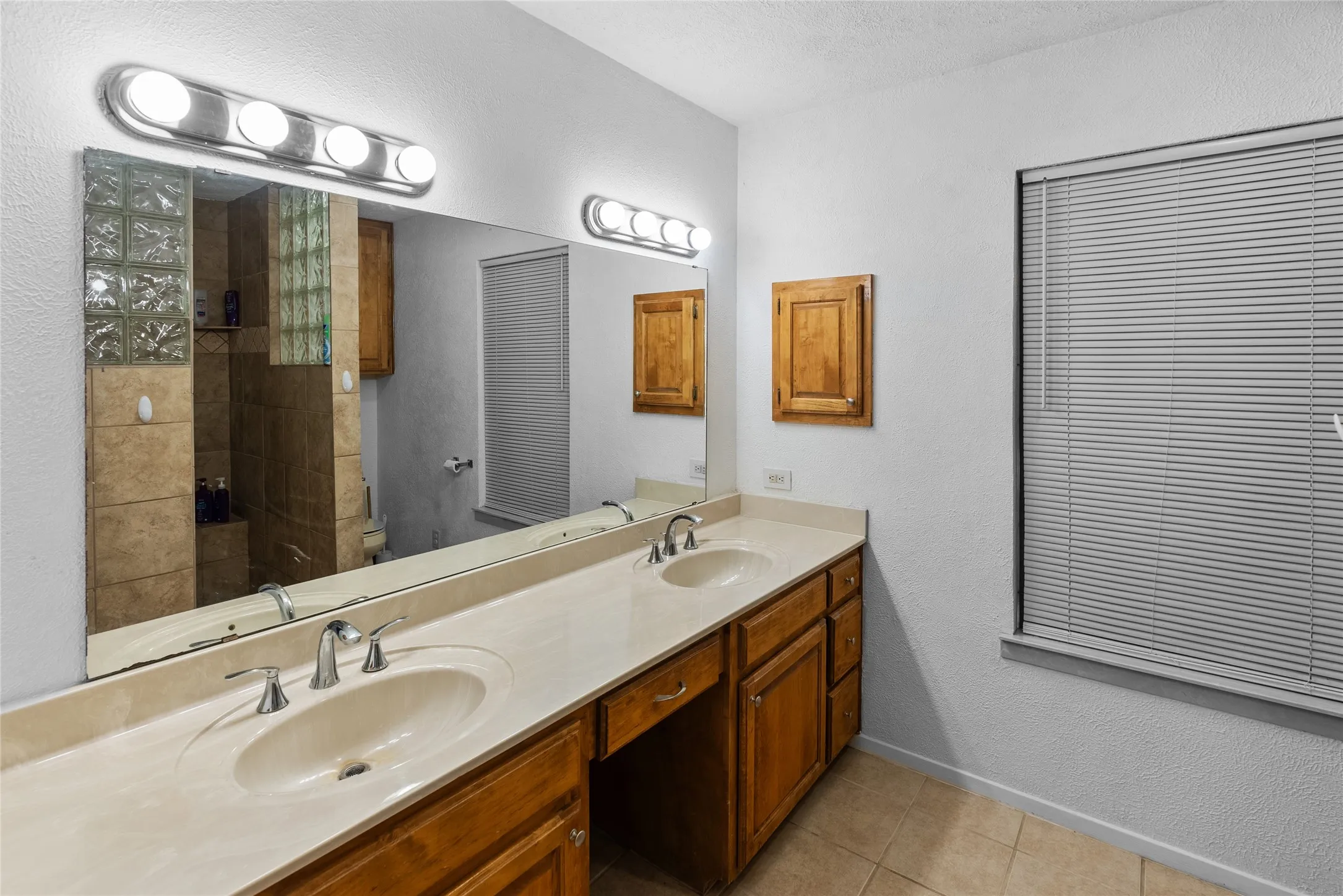 Bathroom with tile patterned floors, double vanity, a sink, and toilet