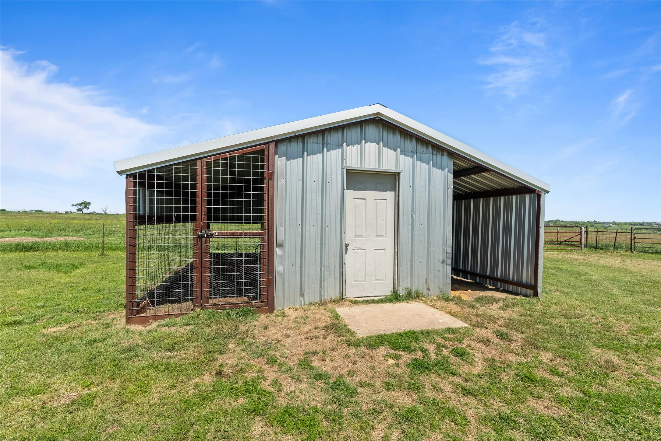 View of outbuilding featuring fence, an outdoor structure, and a rural view