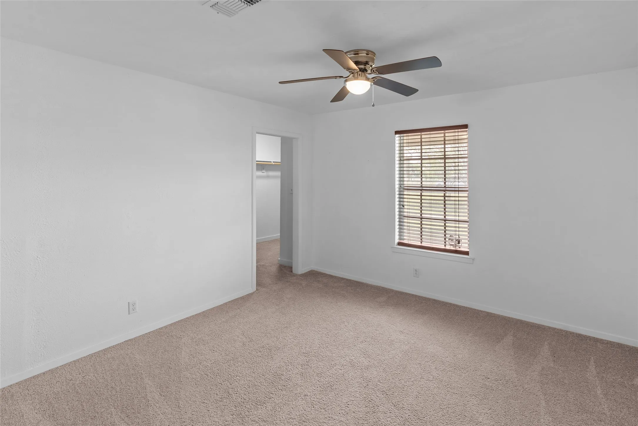 Spare room featuring carpet flooring, visible vents, baseboards, and a ceiling fan