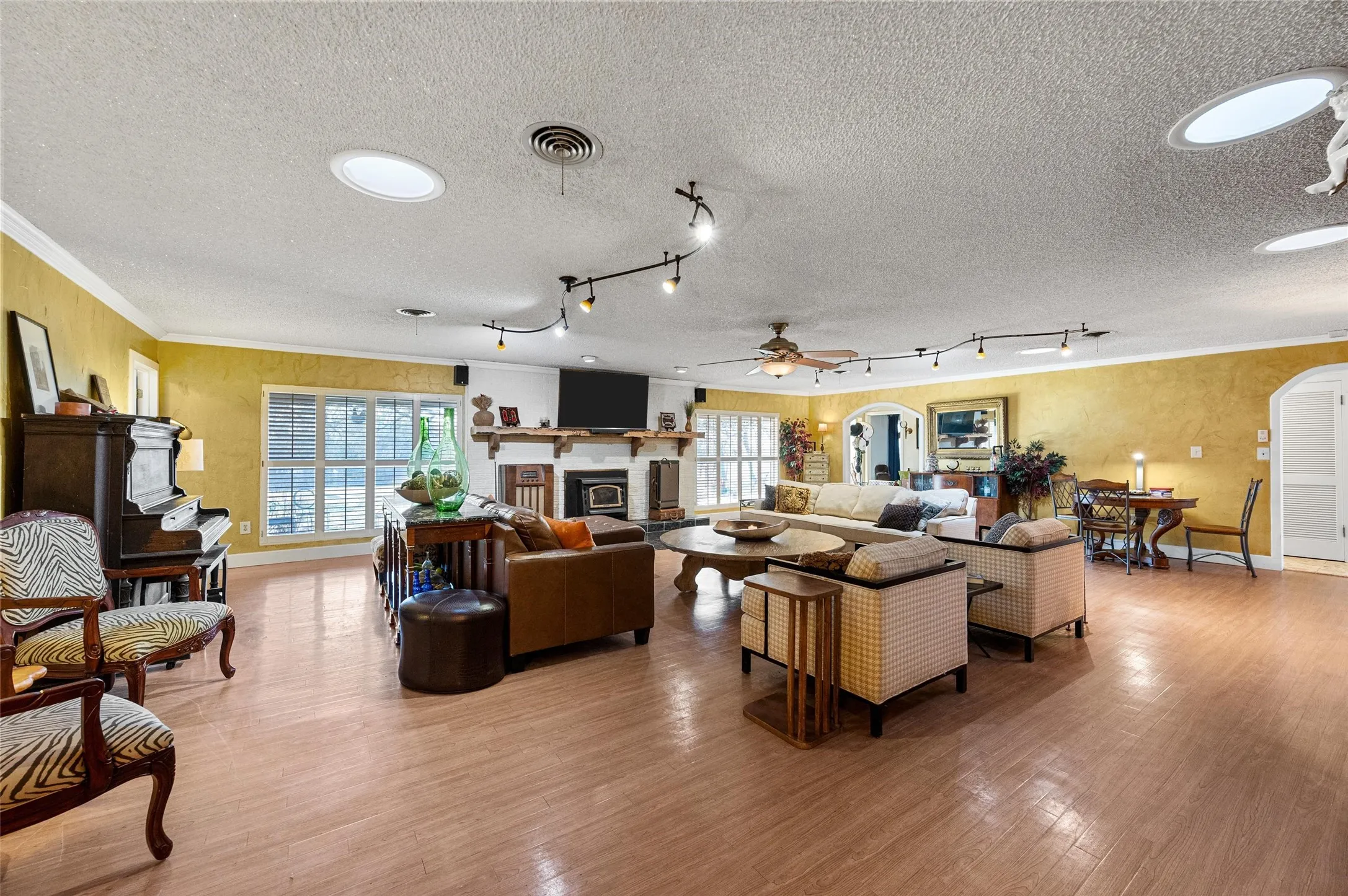 Living room featuring visible vents, baseboards, light wood finished floors, and a glass covered fireplace