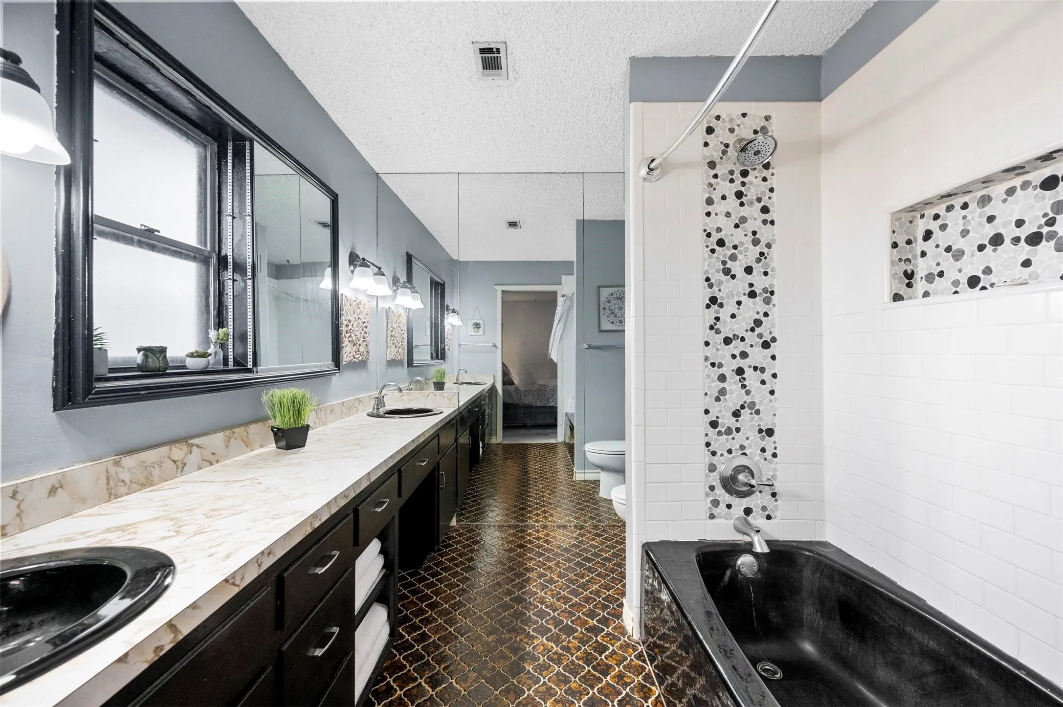 Bathroom featuring a textured ceiling, visible vents, toilet, a sink, and double vanity