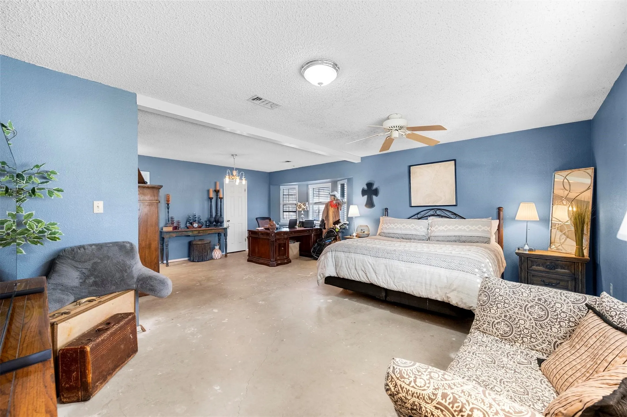 Bedroom featuring visible vents, ceiling fan with notable chandelier, finished concrete flooring, and a textured ceiling