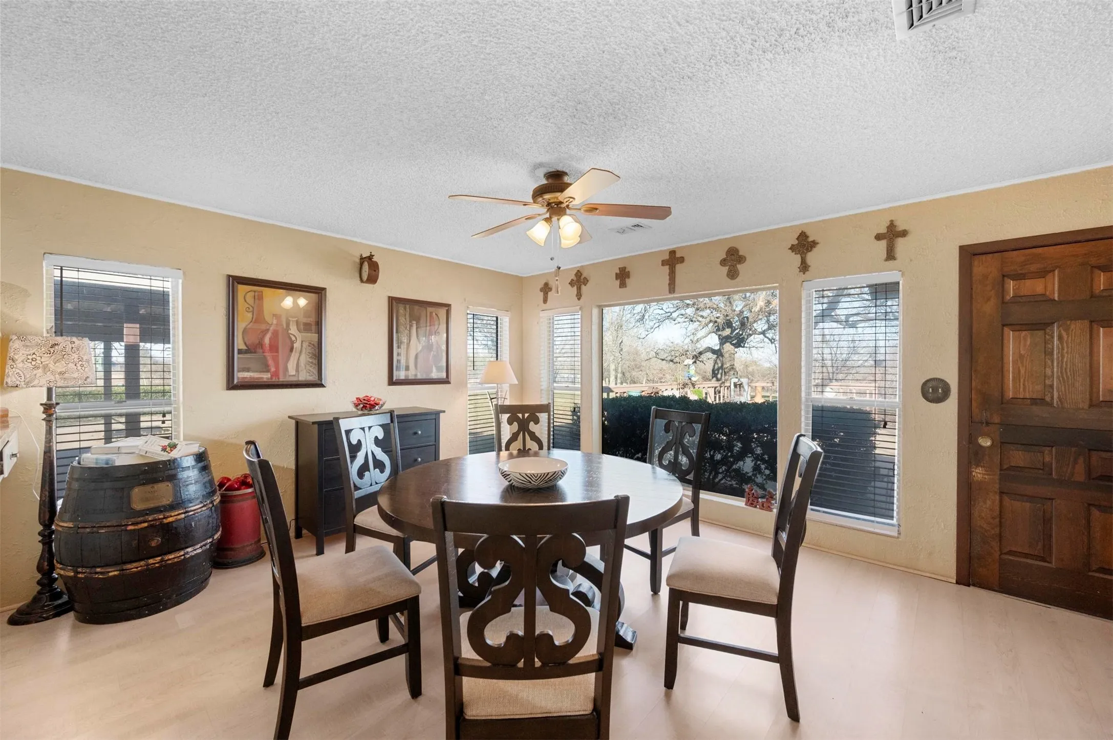 Dining area with visible vents, ceiling fan, light wood-type flooring, and a textured ceiling