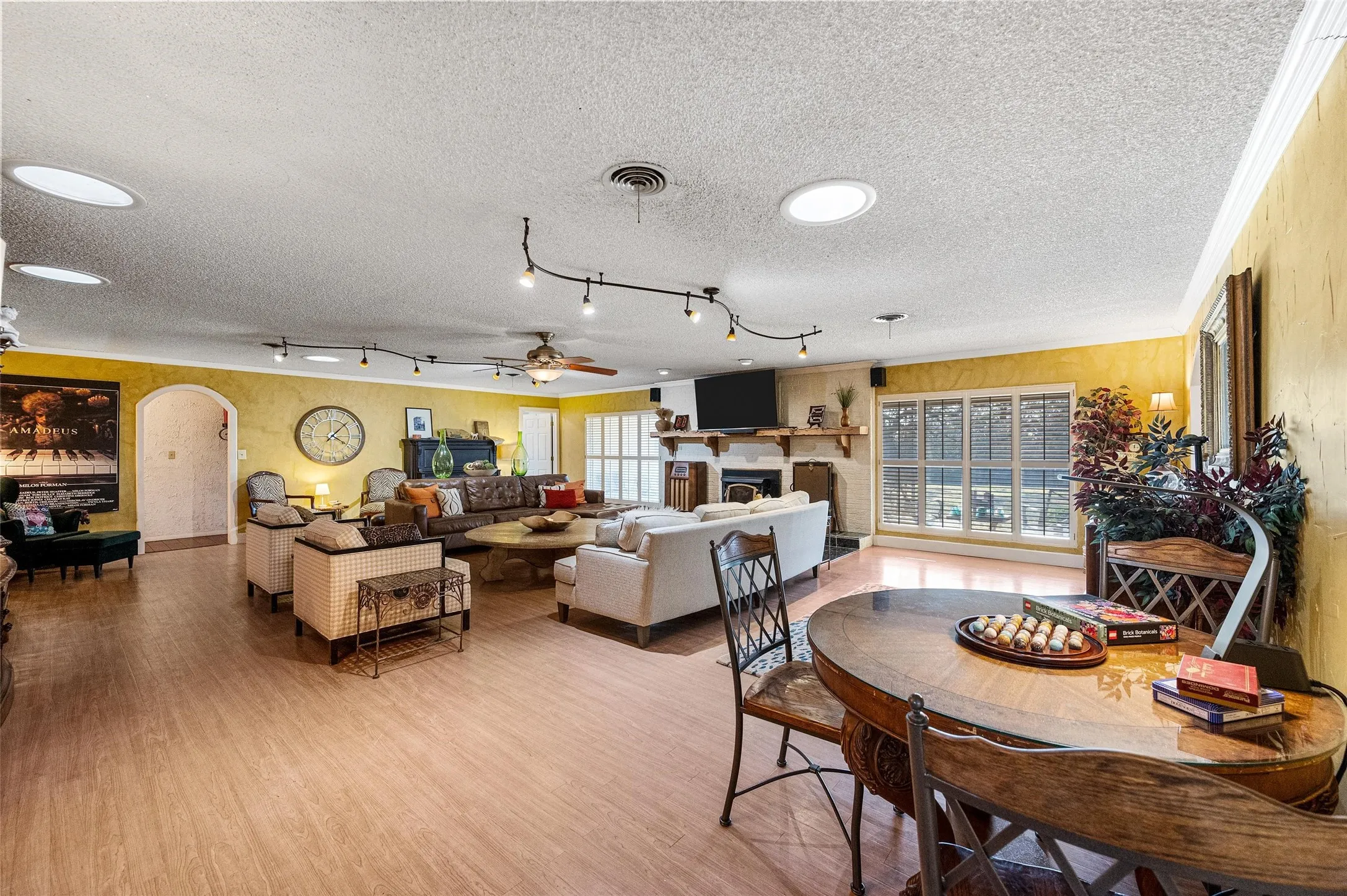 Dining room with a fireplace, arched walkways, a textured ceiling, visible vents, and wood finished floors