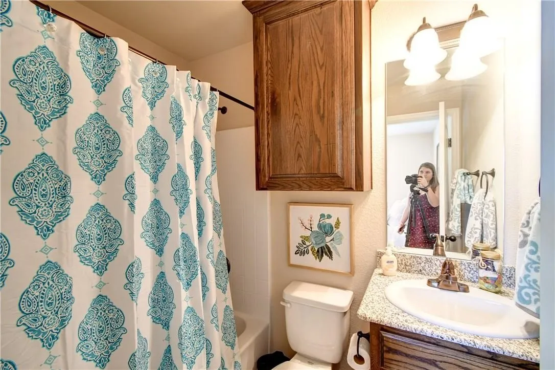 Bathroom featuring vanity and shower / bathtub combination with curtain