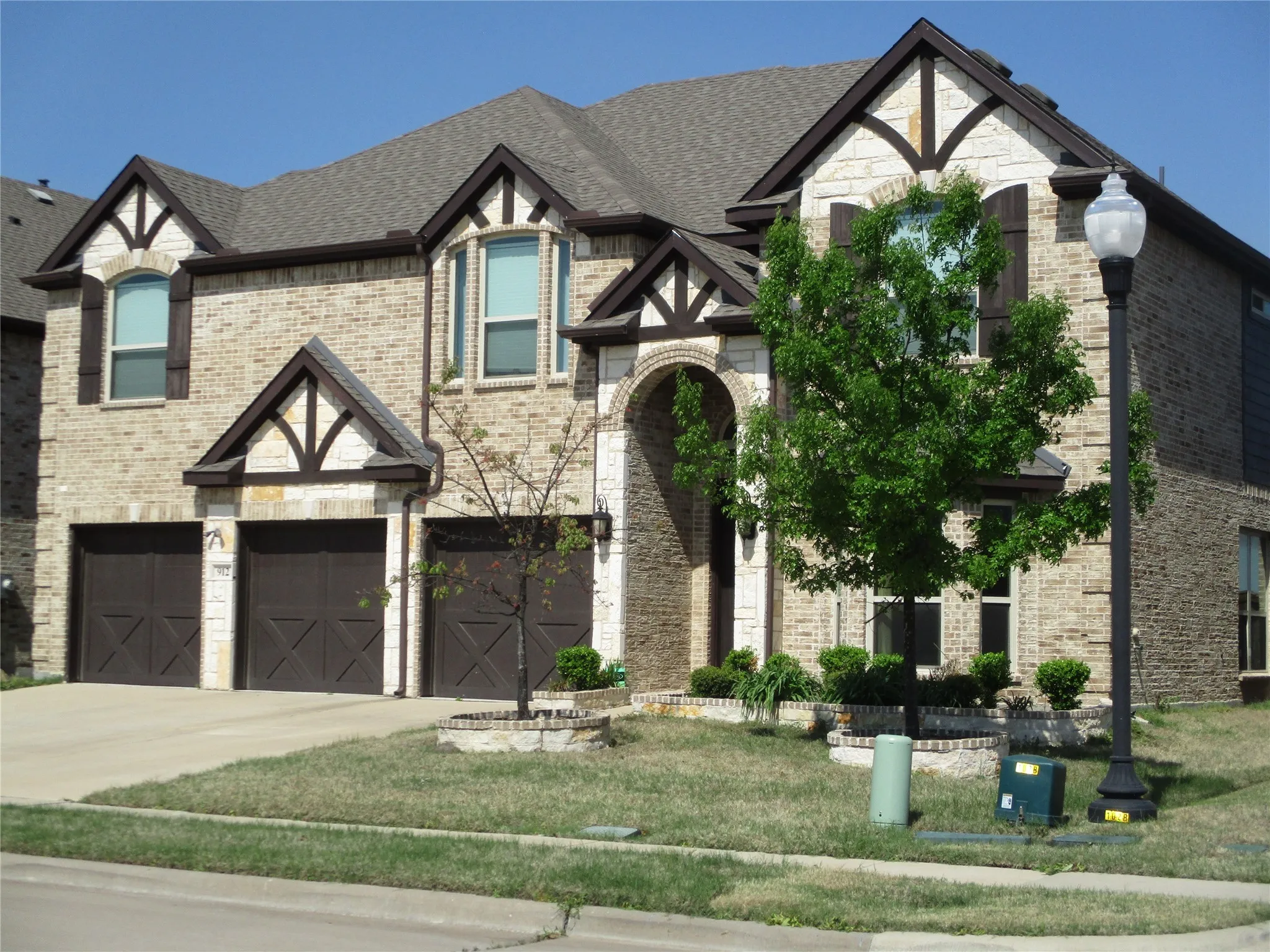View of front of property featuring concrete driveway, an attached garage, a front yard, brick siding, and a shingled roof