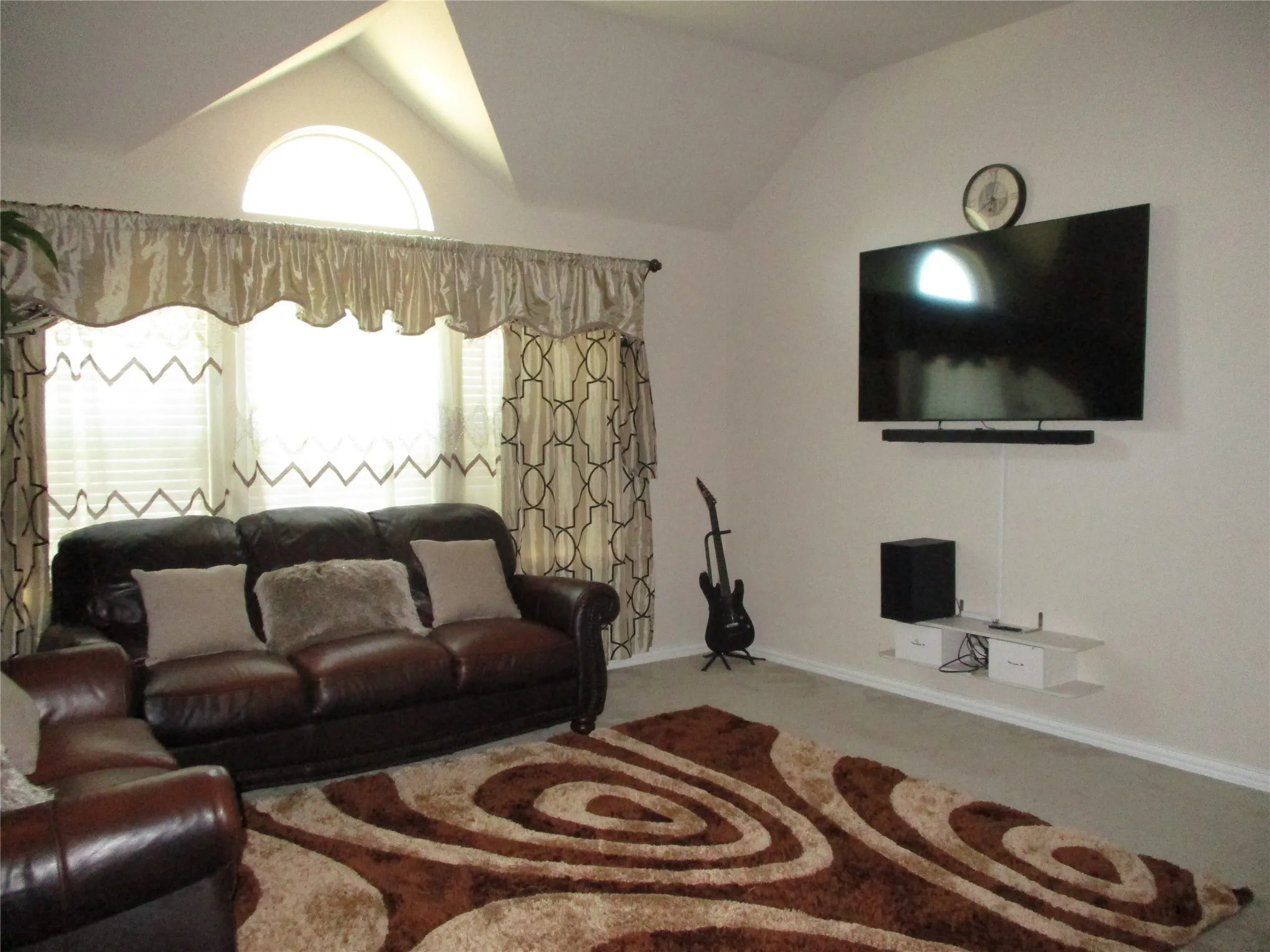 Carpeted living room featuring baseboards and vaulted ceiling