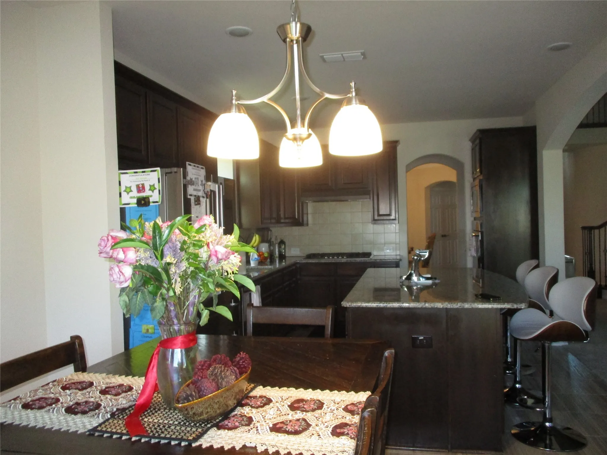 Kitchen featuring tasteful backsplash, gas cooktop, a kitchen island with sink, visible vents, and arched walkways