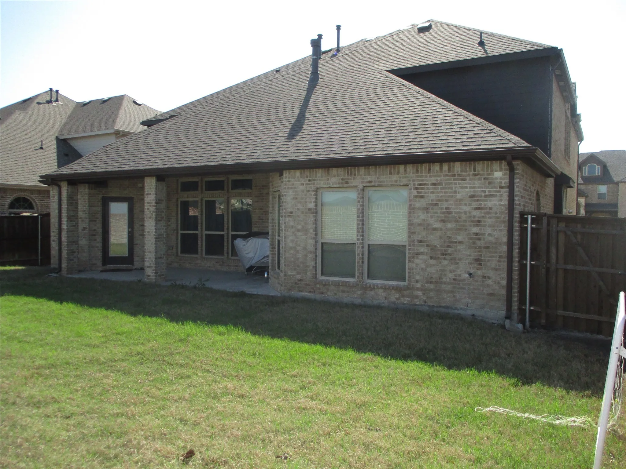 Back of property featuring a lawn, roof with shingles, a patio area, fence, and brick siding