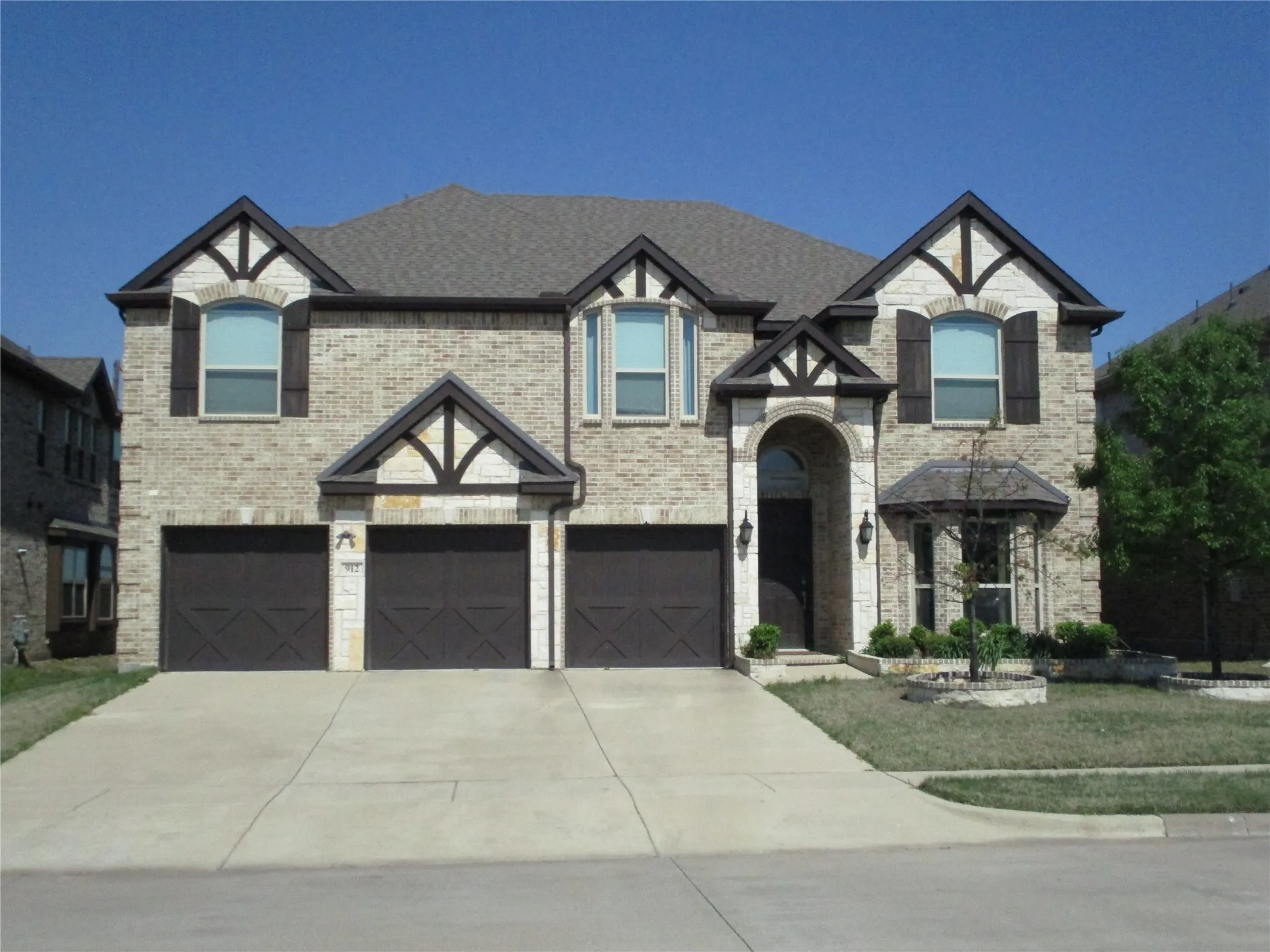 View of front facade featuring brick siding, an attached garage, and driveway