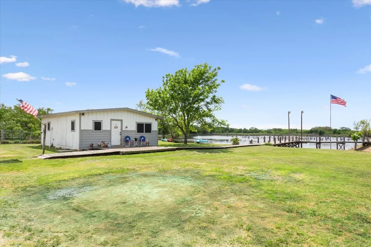 View of yard featuring a deck with water view and fence