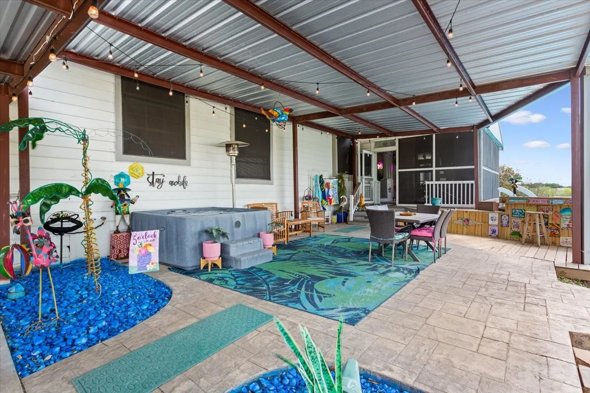 View of patio with outdoor dining space, a sunroom, and a​​‌​​​​‌​​‌‌​‌‌​​​‌‌​‌​‌​‌​​​‌​​ jacuzzi