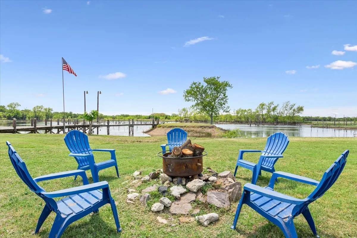 View of community featuring a lawn, a water view, and an outdoor fire pit