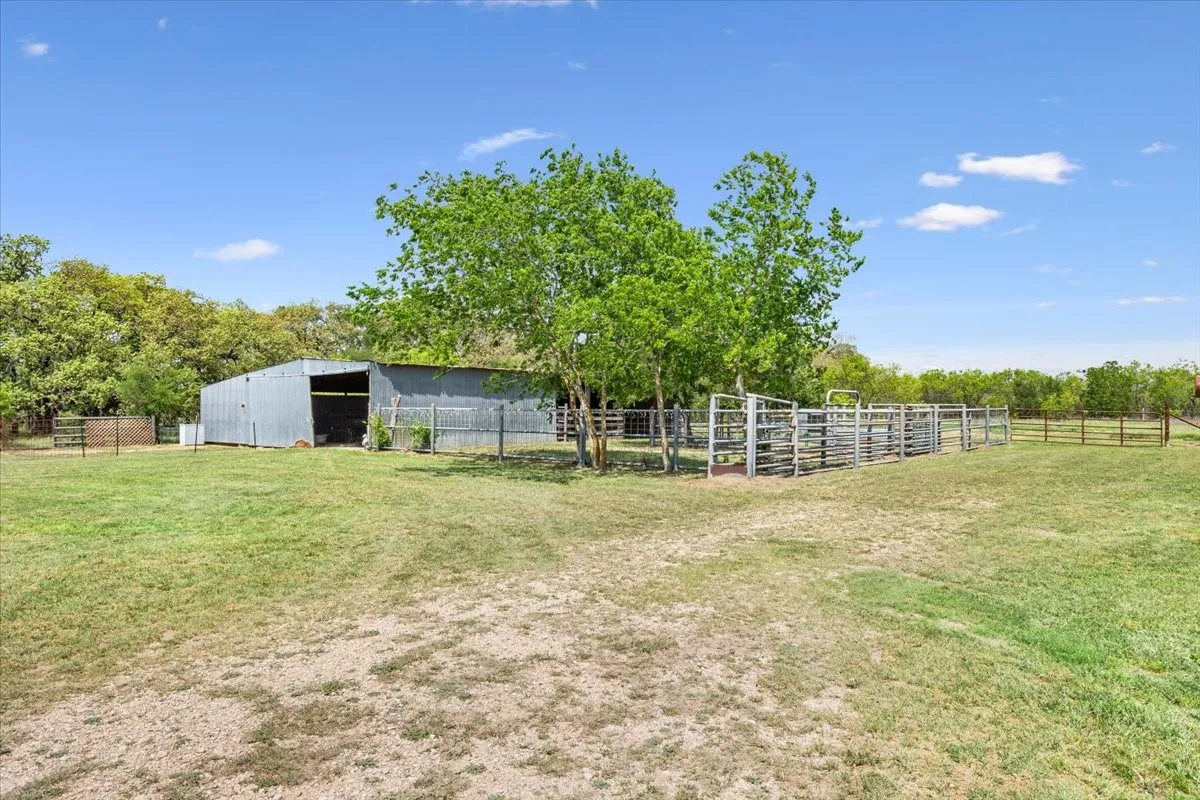 View of yard with a pole building, an outbuilding, and fence