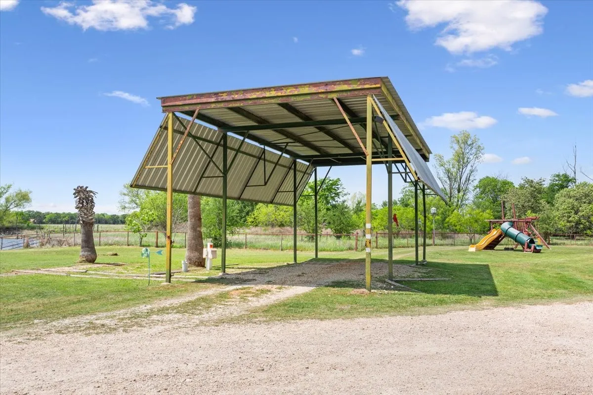 View of home's community with driveway, fence, a yard, and a detached carport