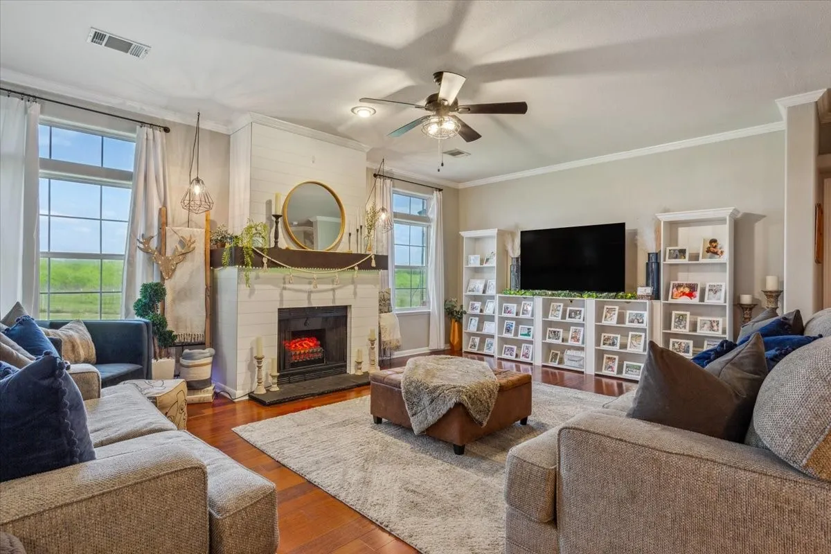 Living area featuring plenty of natural light, visible vents, a fireplace, and ceiling fan