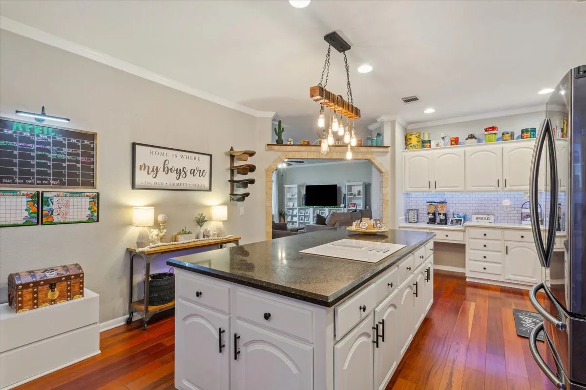 Kitchen with dark countertops, visible vents, freestanding refrigerator, a kitchen island, and crown molding