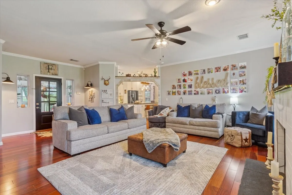 Living room featuring dark wood finished floors, visible vents, and a ceiling fan