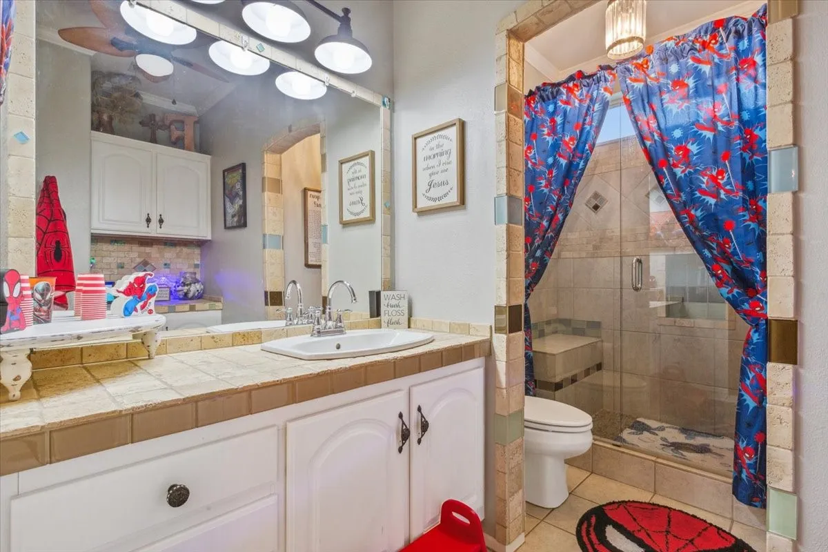 Full bath with tile patterned flooring, toilet, vanity, tasteful backsplash, and a stall shower