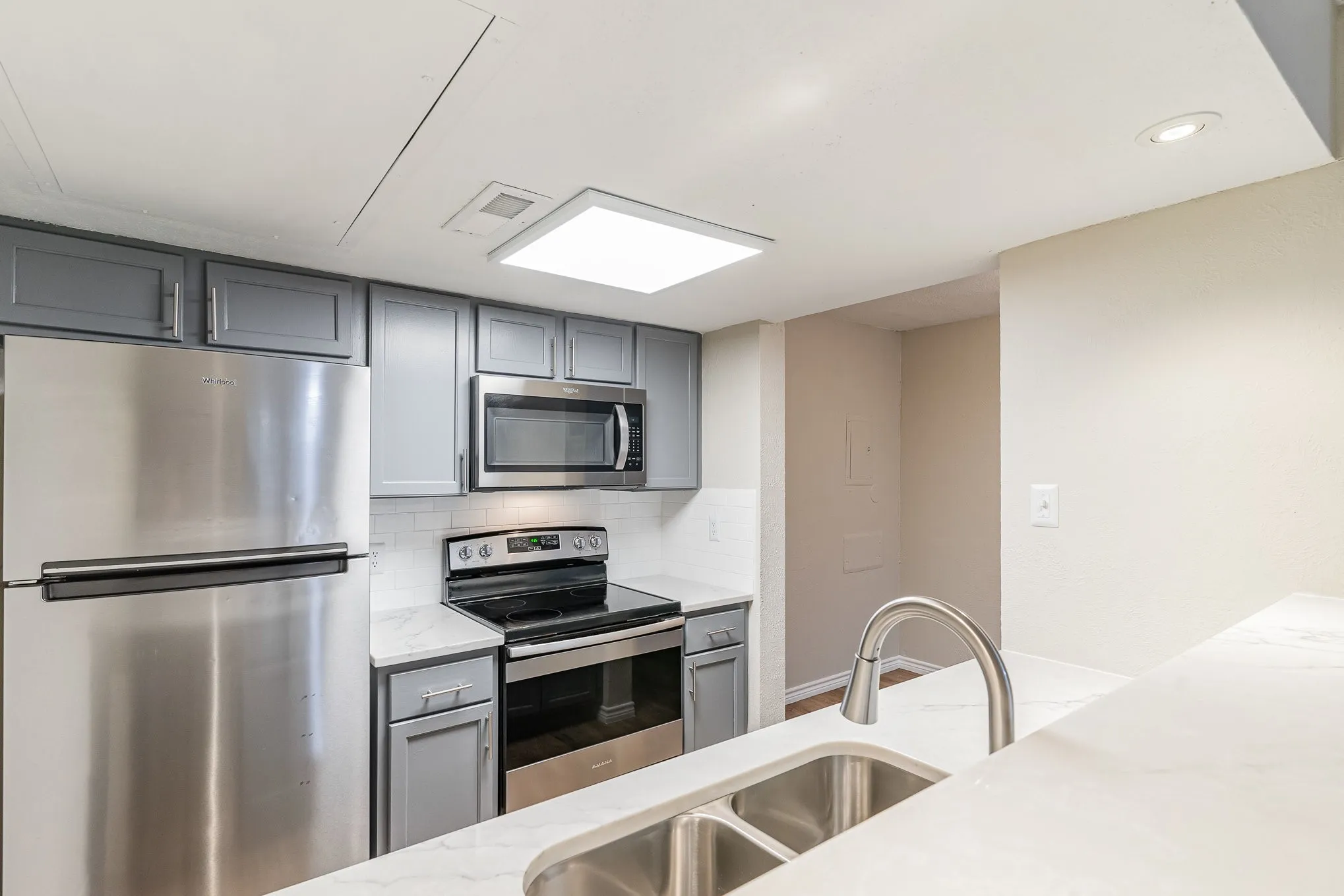 Kitchen featuring gray cabinets, tasteful backsplash, stainless steel appliances, and a sink