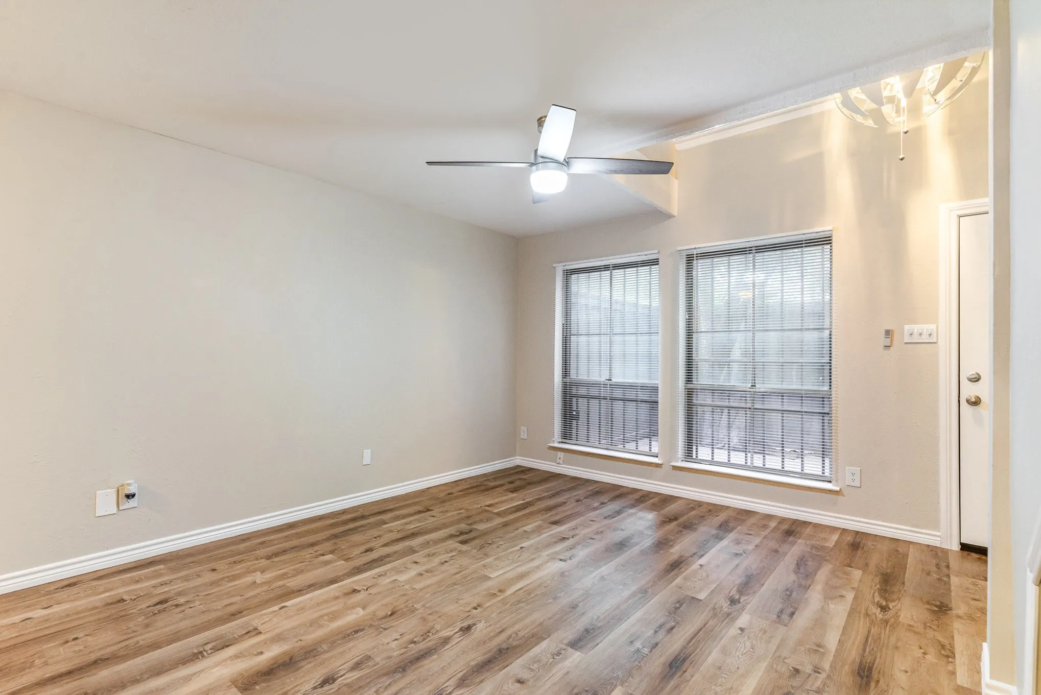 Spare room featuring baseboards, wood finished floors, and ceiling fan with notable chandelier