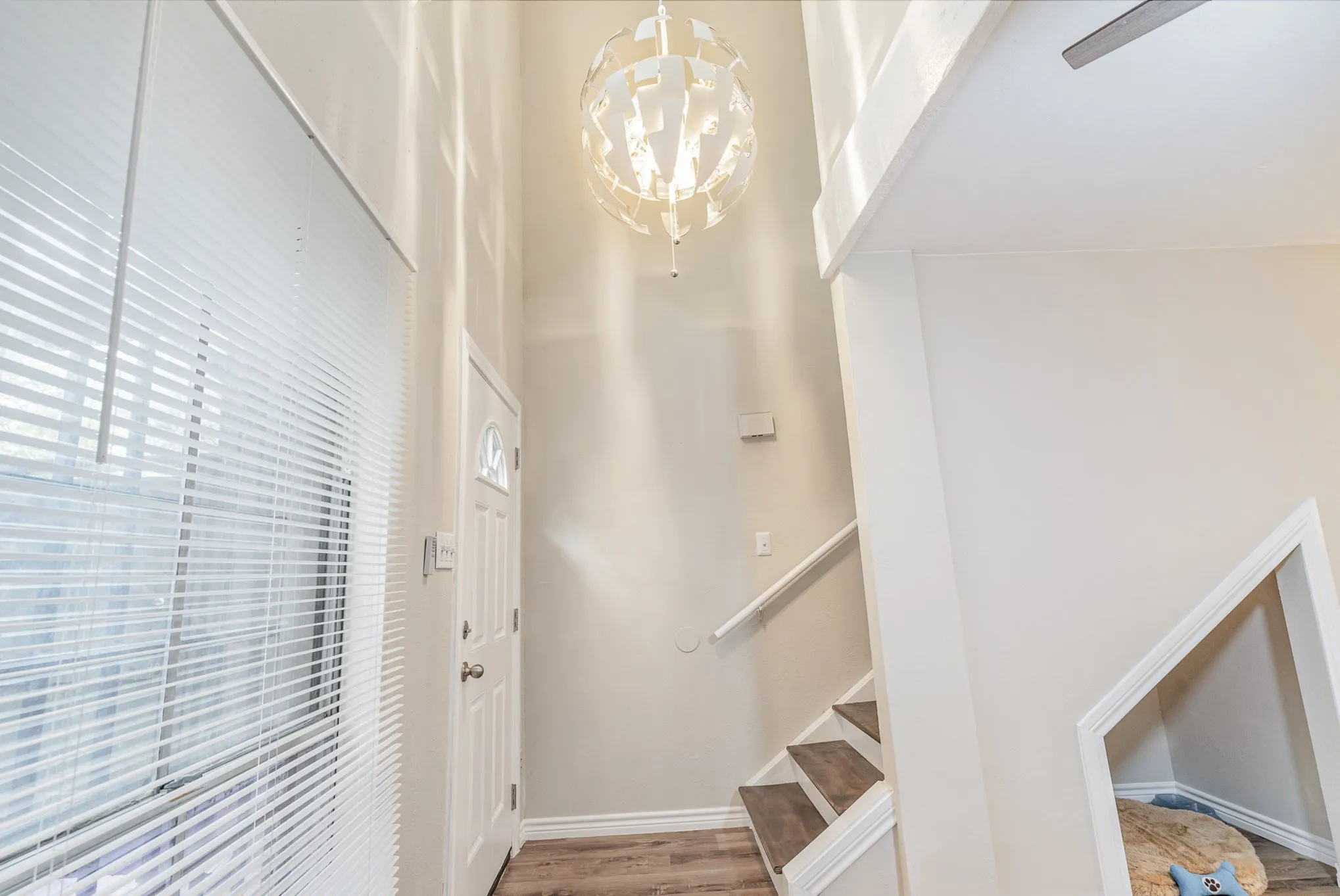 Stairway featuring a towering ceiling, a notable chandelier, wood finished floors, and baseboards