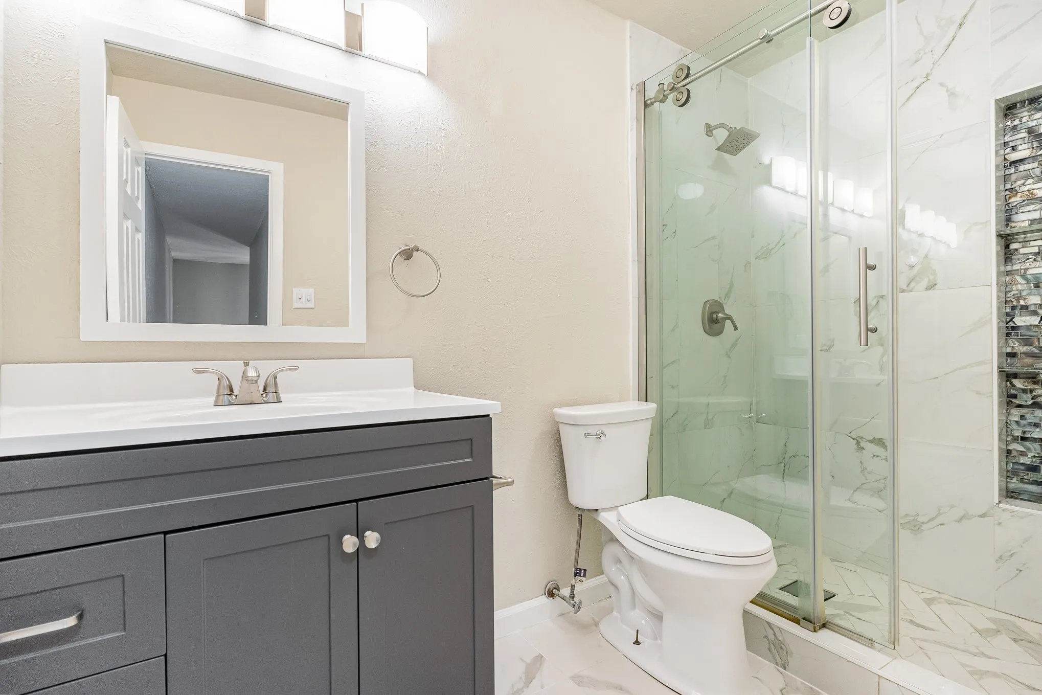 Bathroom featuring marble finish floor, vanity, a marble finish shower, and toilet
