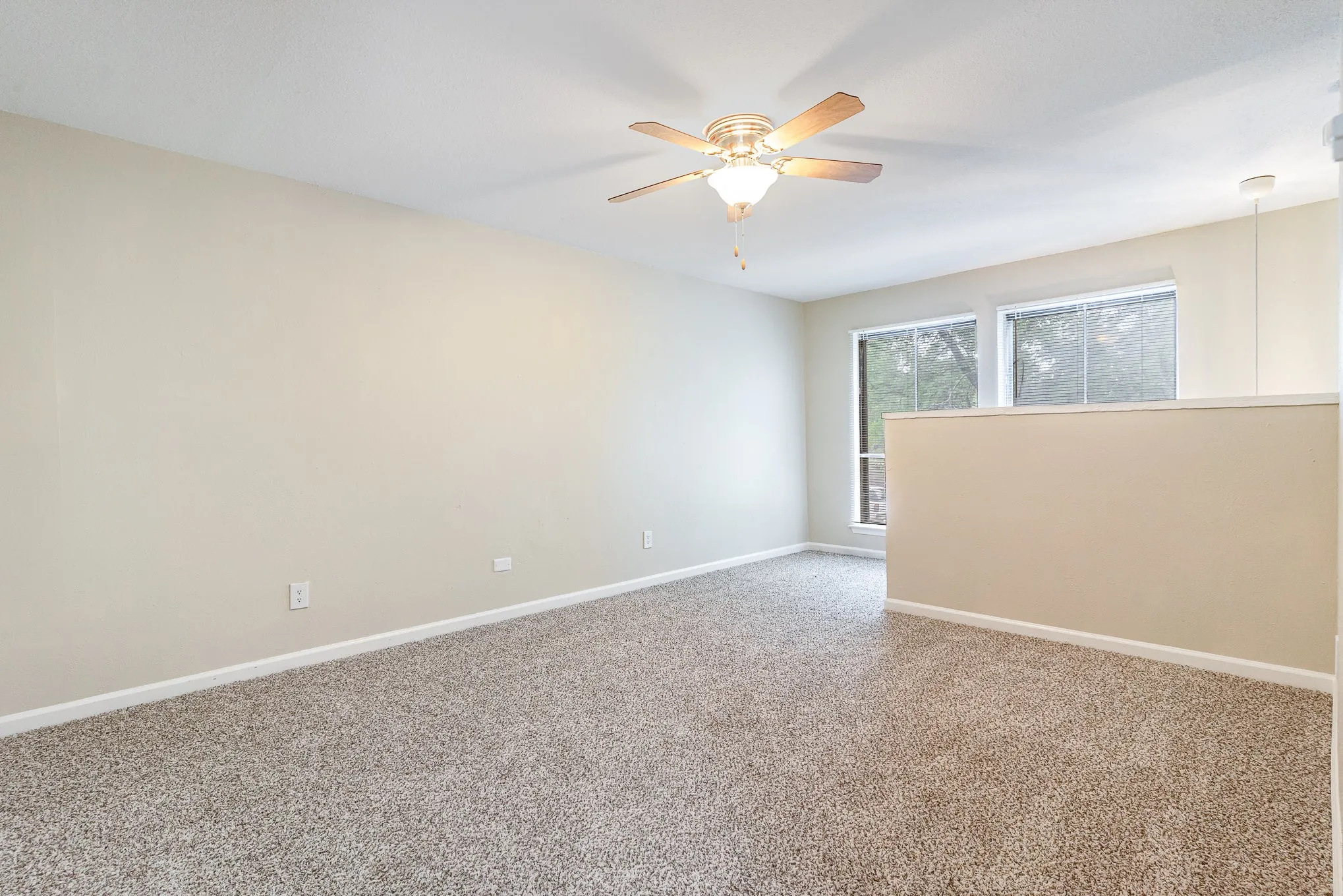 Carpeted spare room featuring baseboards and a ceiling fan