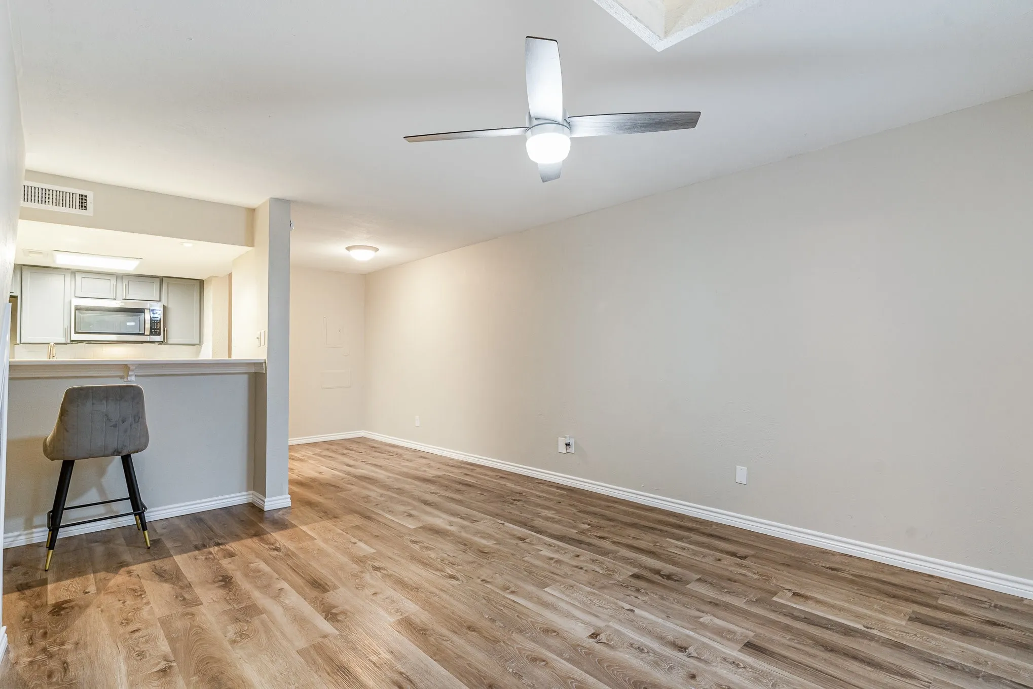 Unfurnished living room featuring baseboards, a ceiling fan, visible vents, and light wood-style floors