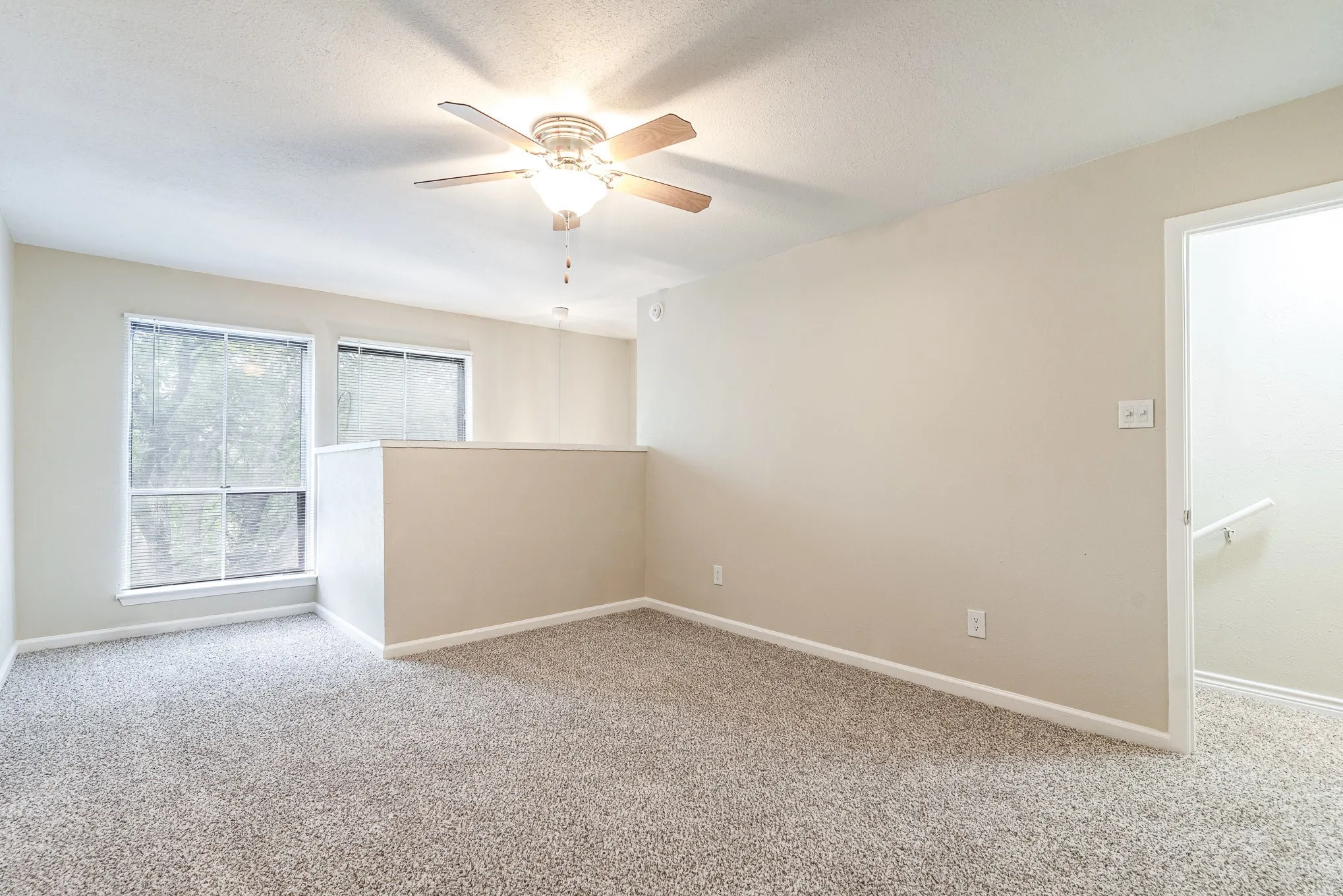 Carpeted empty room featuring a ceiling fan and baseboards