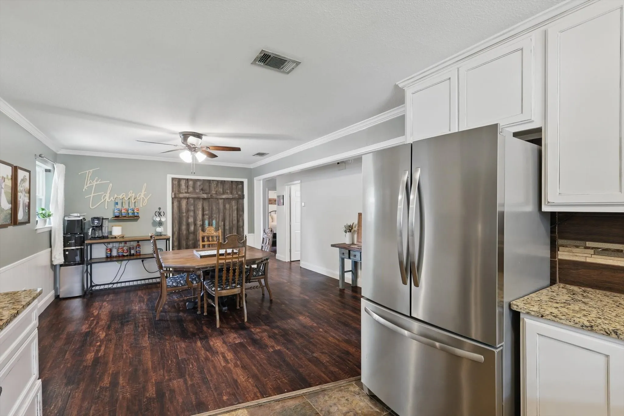 Kitchen featuring ceiling fan, visible vents, crown molding, white cabinets, and freestanding refrigerator
