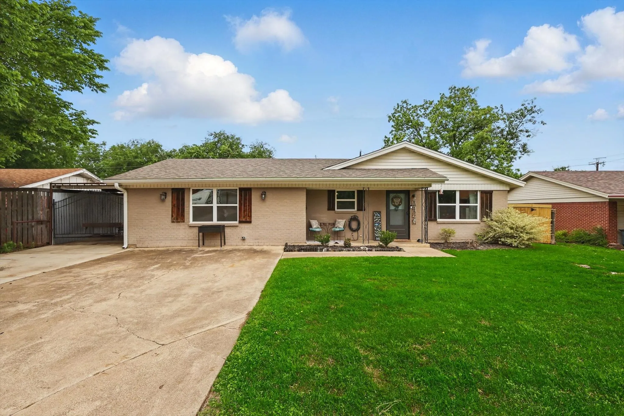 Single story home featuring fence, a shingled roof, brick siding, a front yard, and driveway