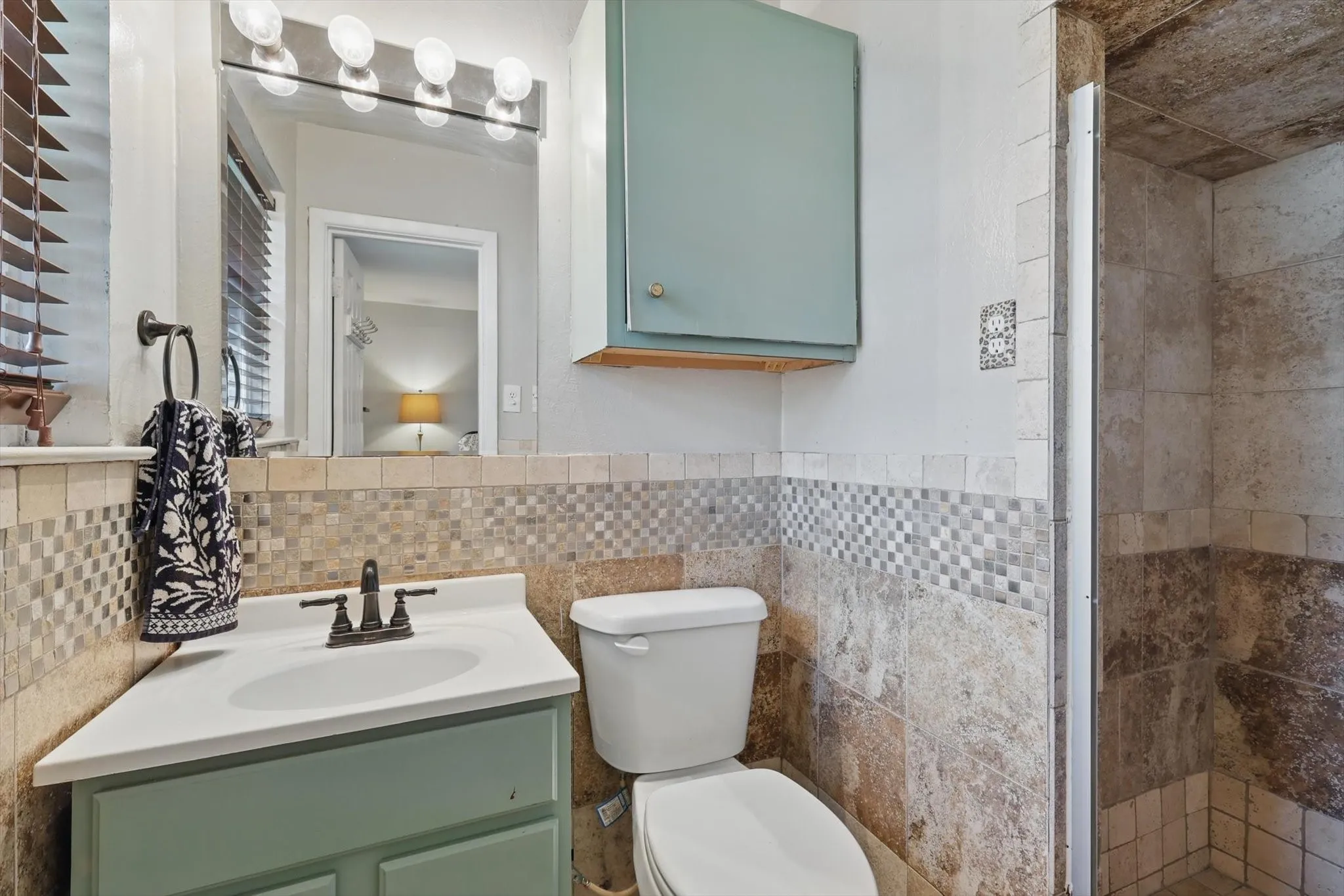 Bathroom with vanity, a tile shower, toilet, and tile walls