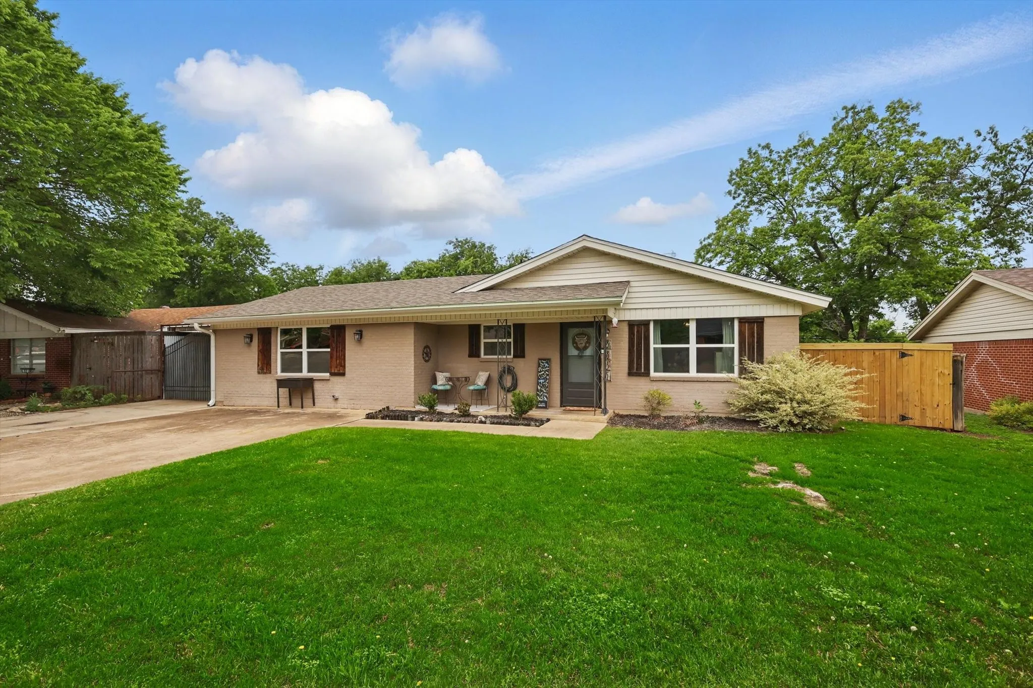 Ranch-style home with a gate, a front lawn, and brick siding